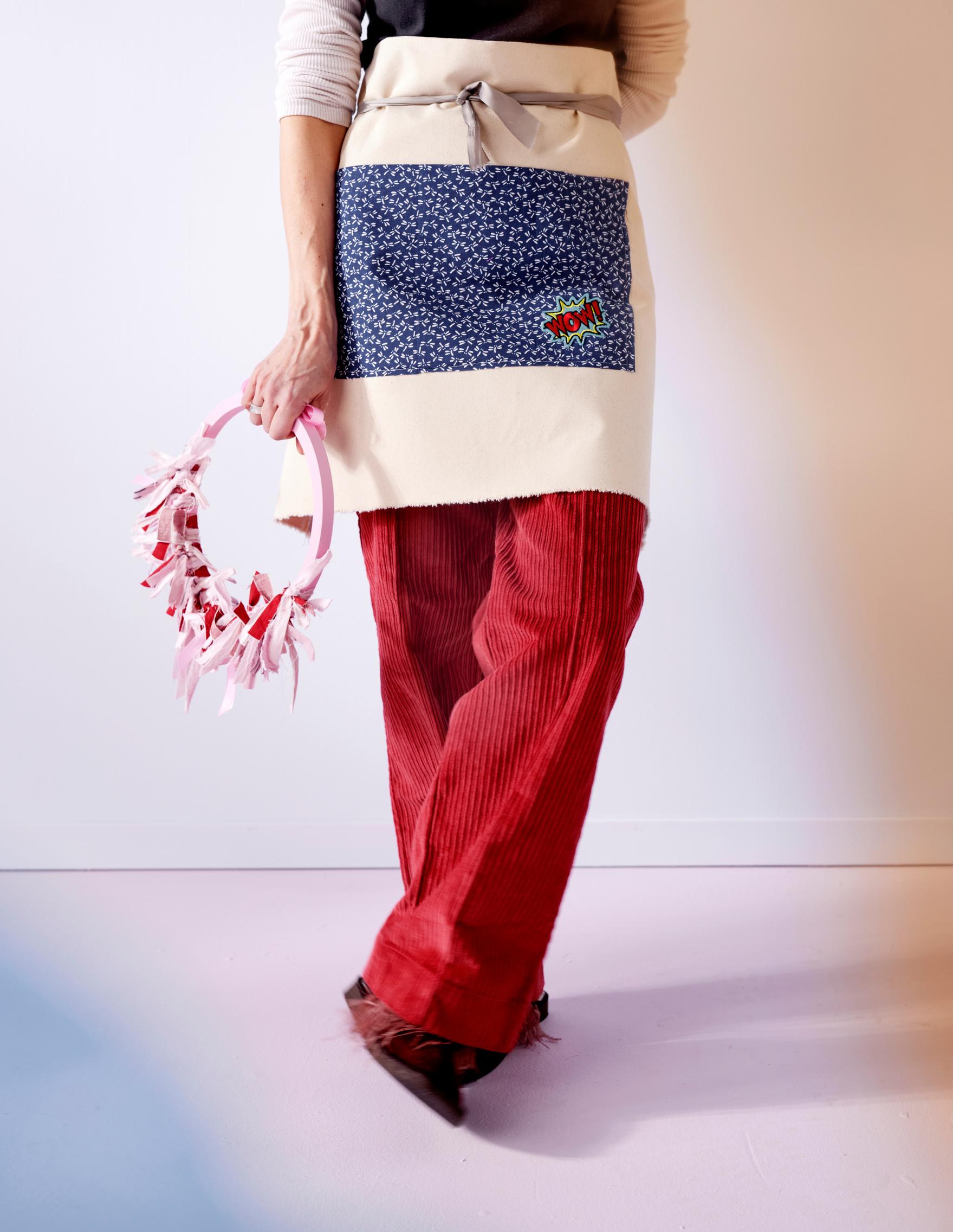 A solid-colored cotton apron with a colorful patchwork fabric pocket.