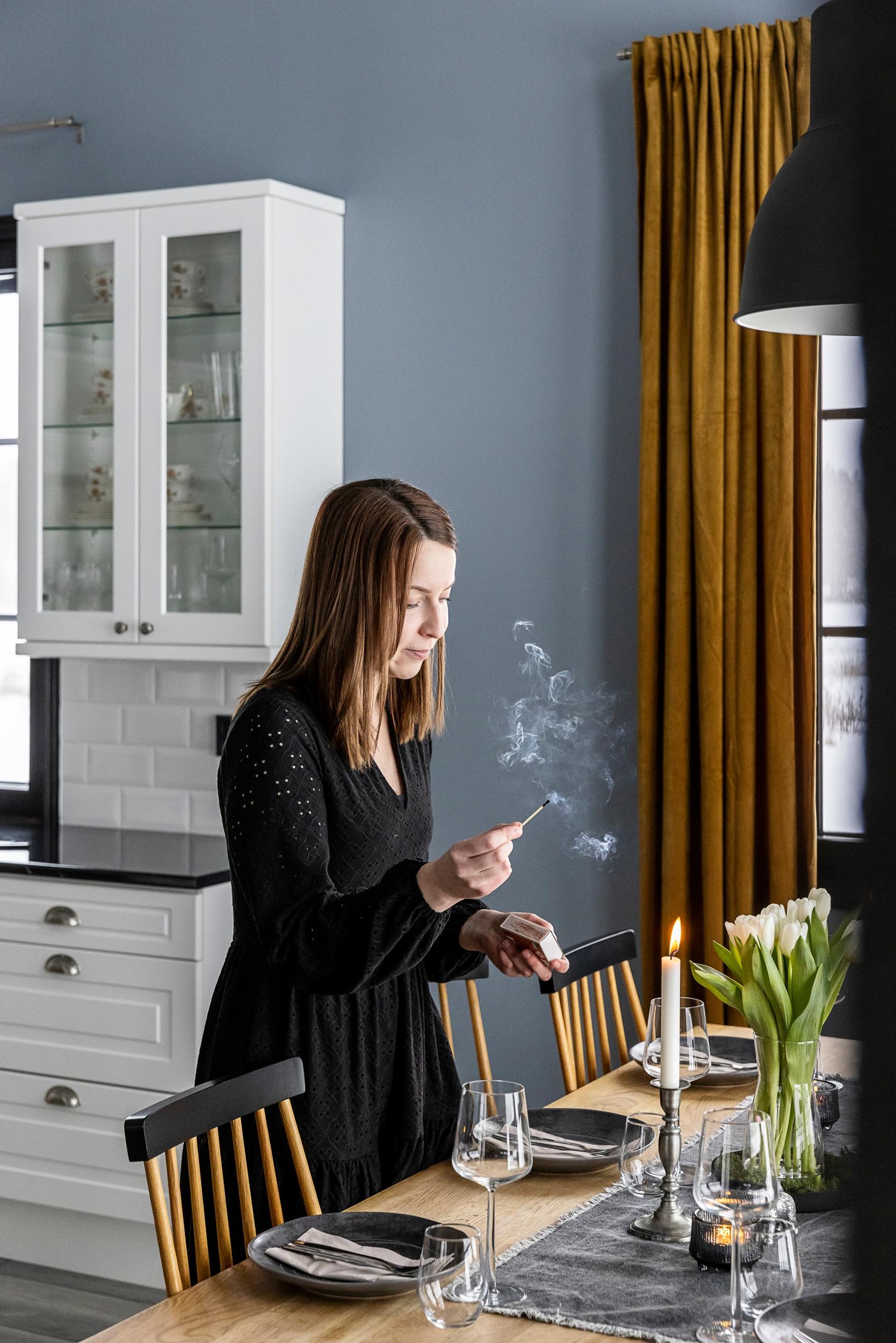 Annika Vestman lighting a candle for a festive table setting.