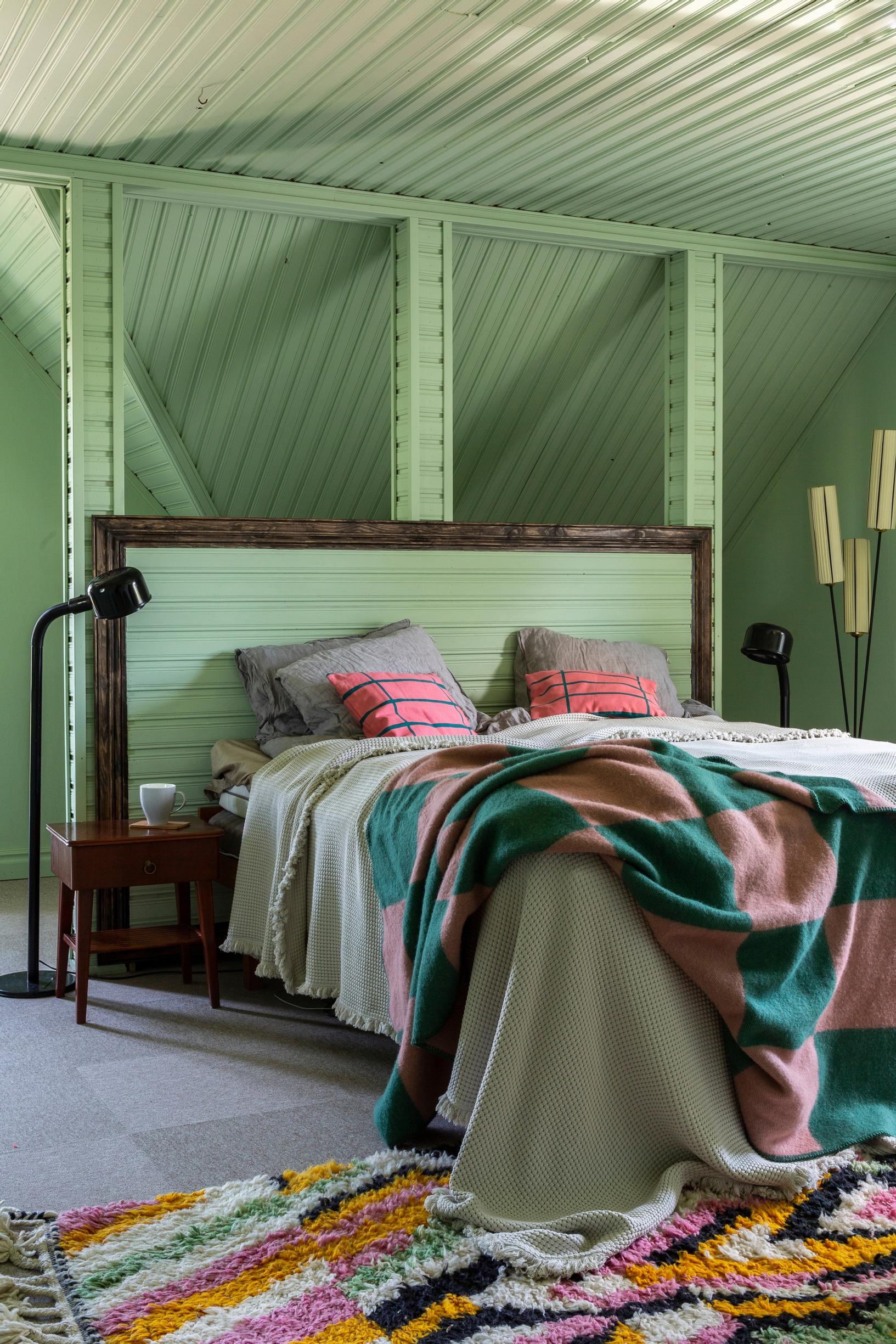 A green bedroom with varied ceiling panels.