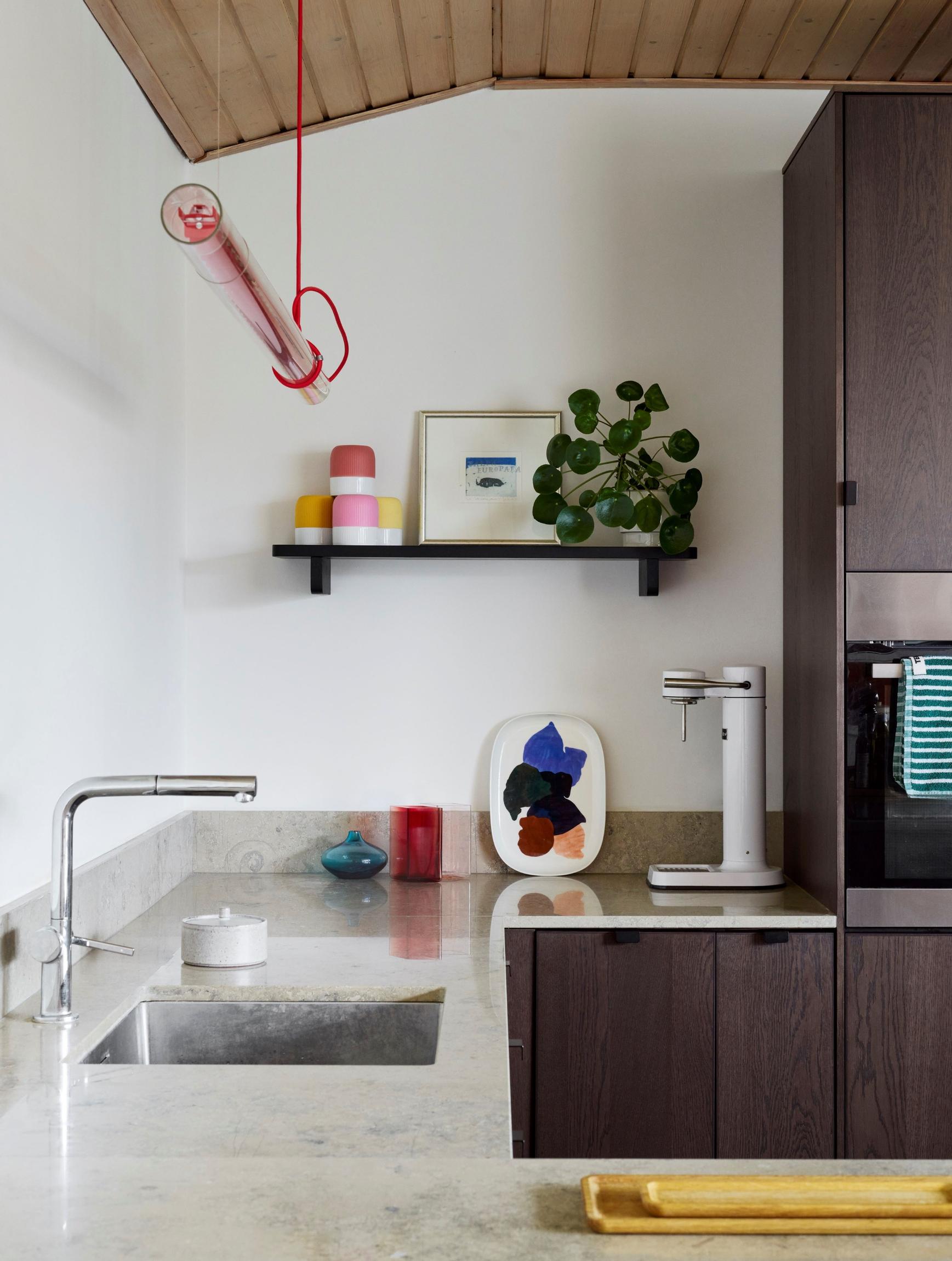 A kitchen with limestone countertops and an elongated pendant light.