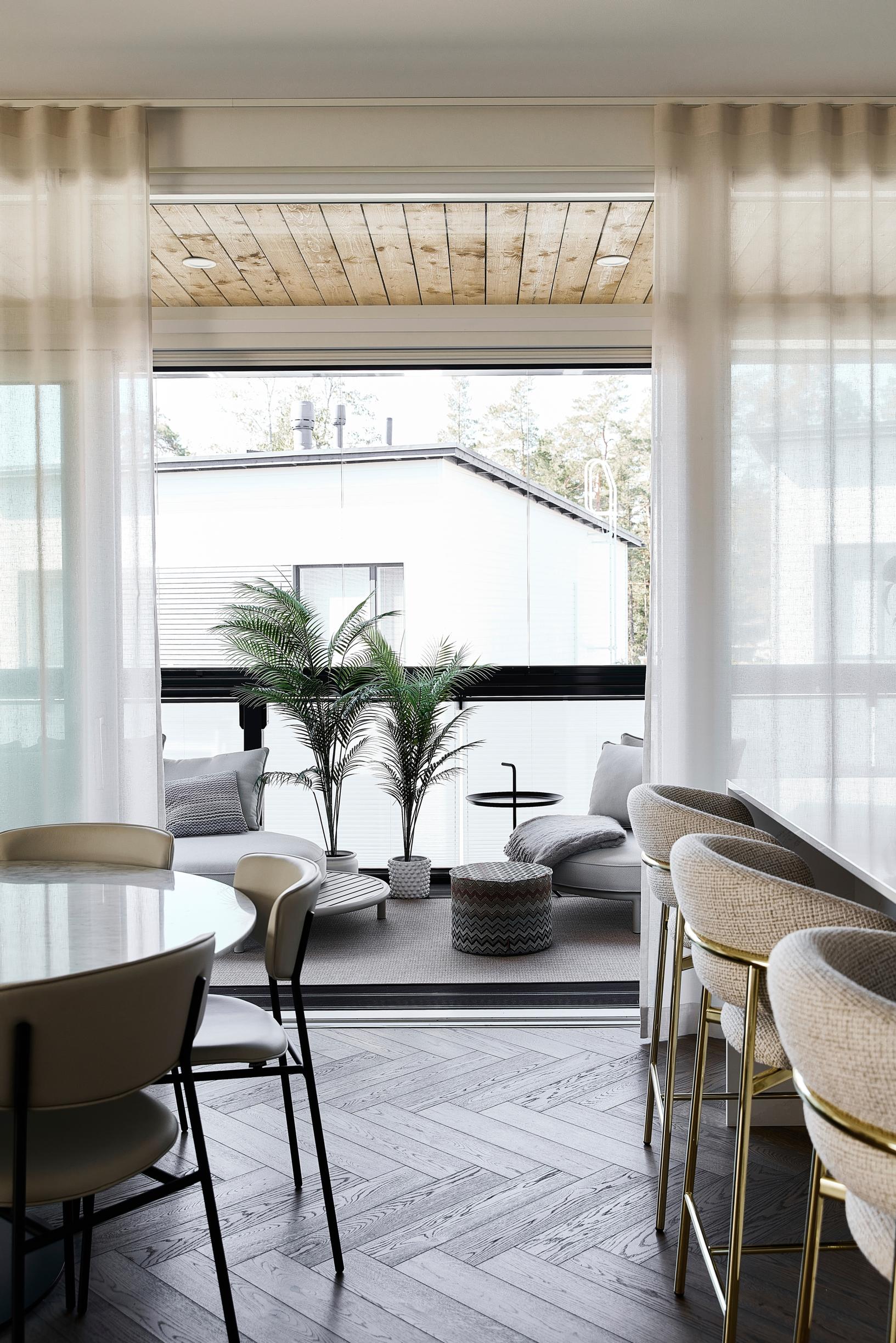 A view from the dining area and kitchen out to the terrace. On the left is the dining table, on the right an island with bar stools.