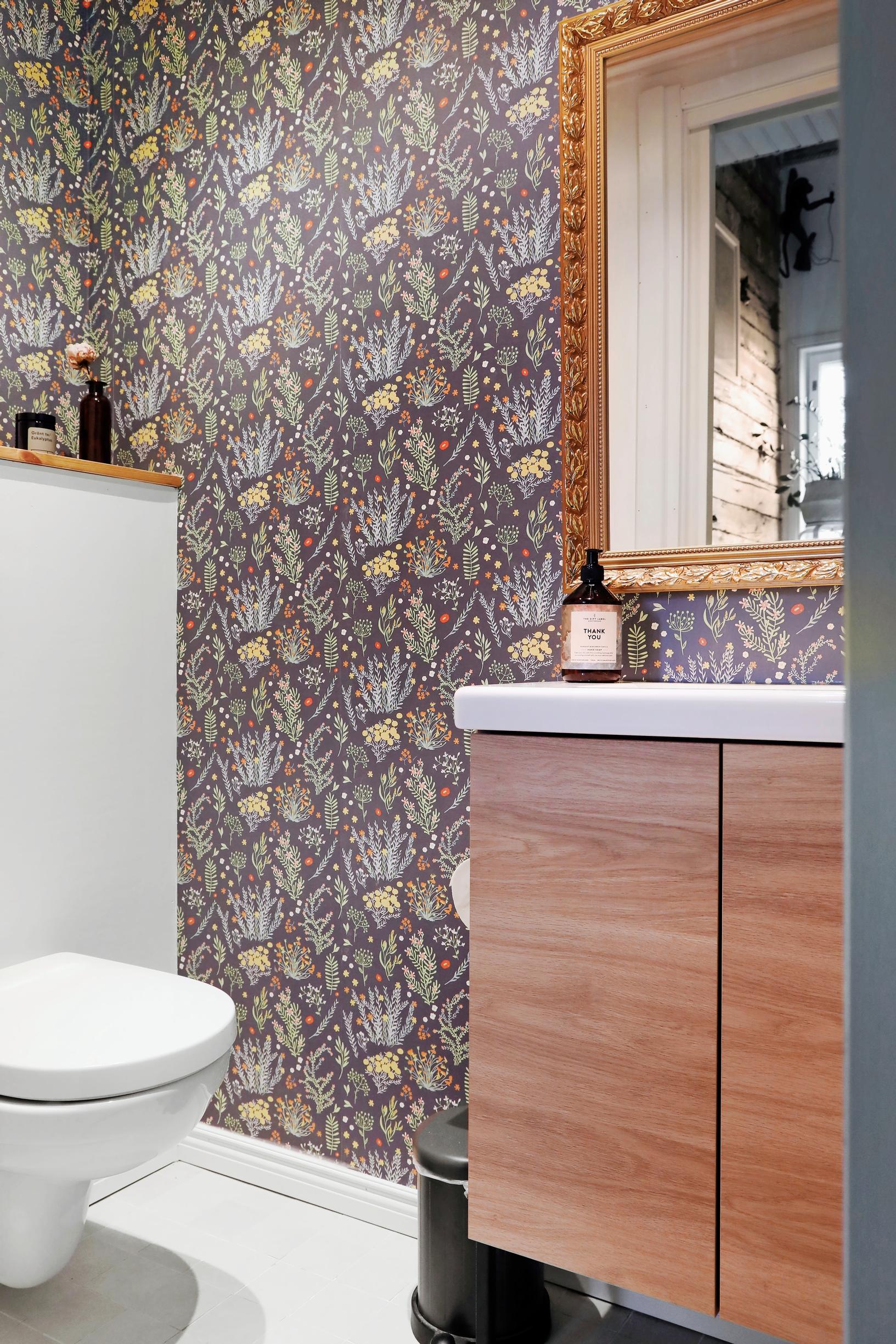 A small restroom with floral wallpaper