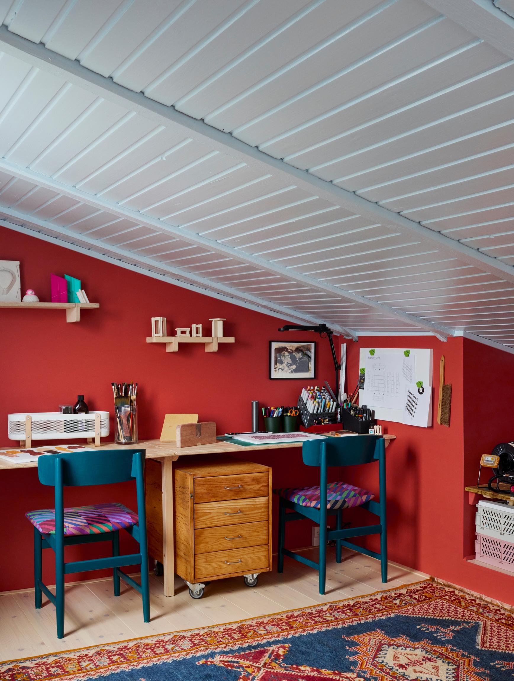 In the workspace, a red wall and open shelves for scale models.