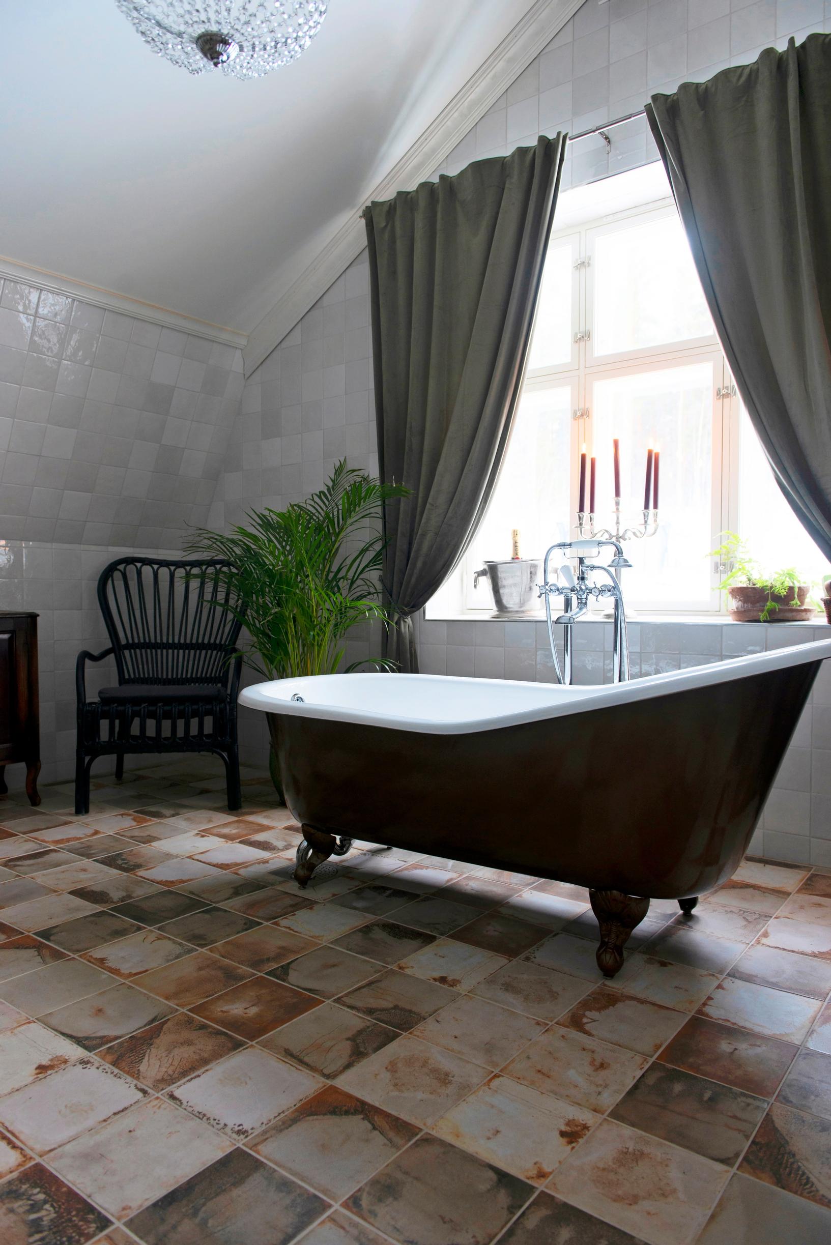 The clawfoot tub sits in front of the window.