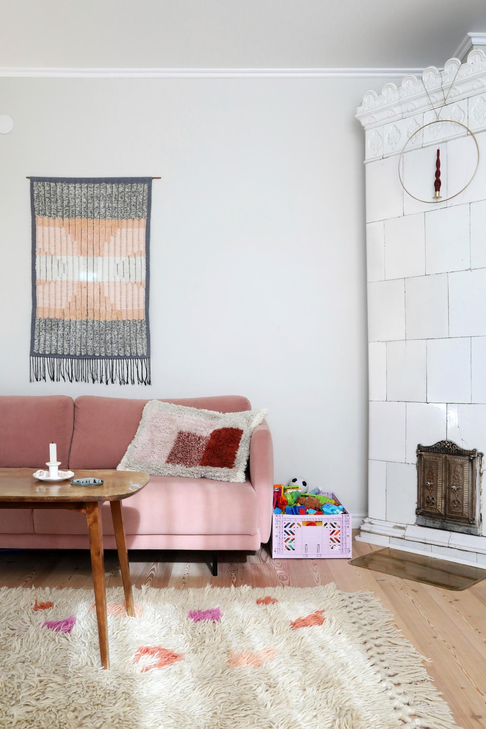 a pink sofa and a tiled stove in the living room