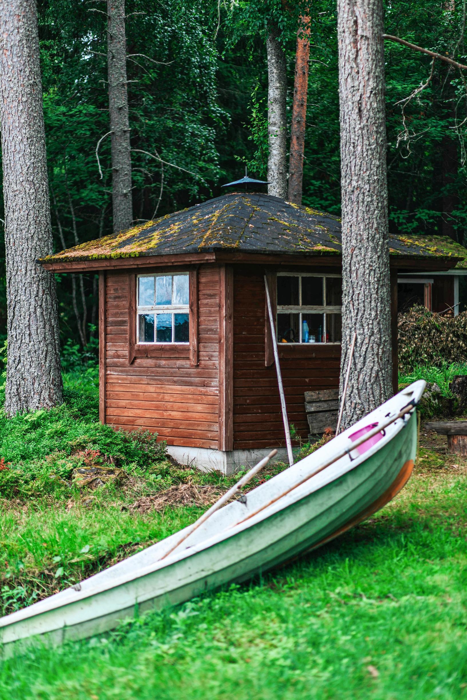 A boat at the shore with an old shed in the background.