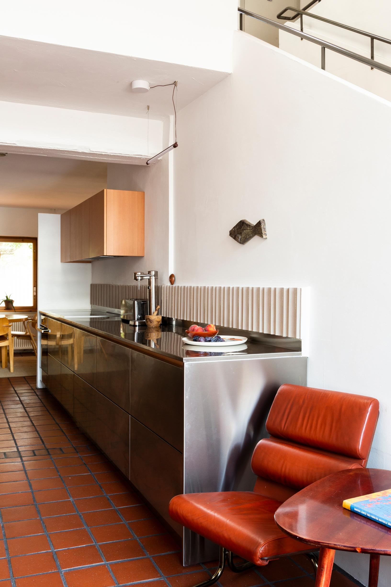 Stainless steel kitchen cabinets, a retro leather armchair and coffee table, tiled floor