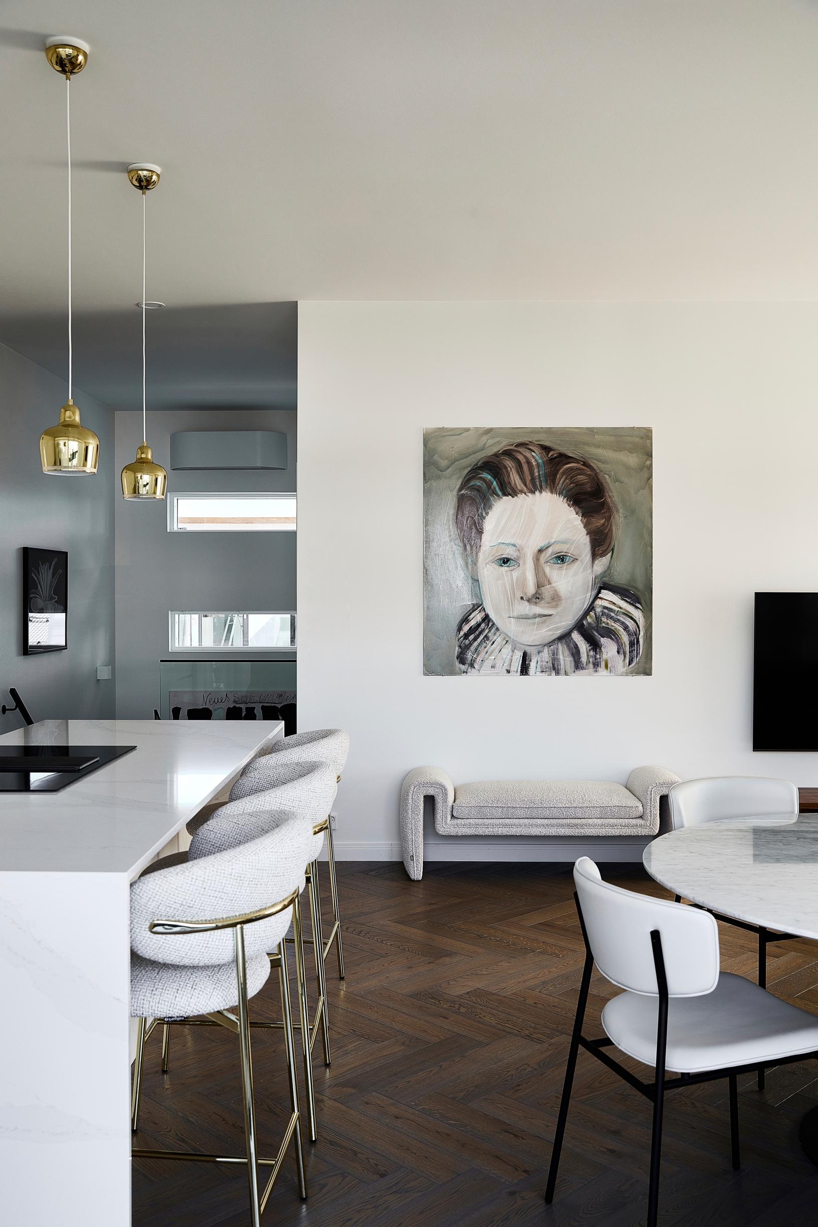 A painting of a female figure on the living room wall. On the left is the island, on the right the dining table.