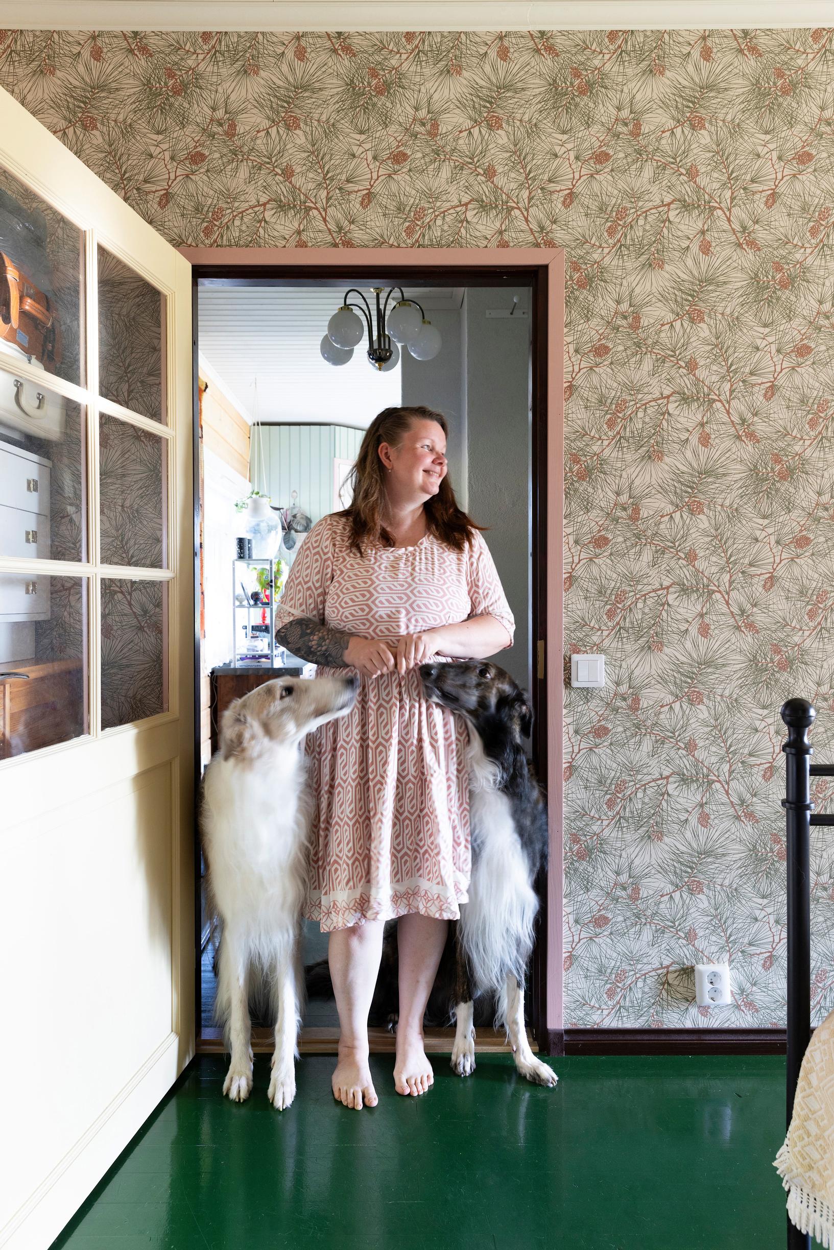 The interviewee stands inside the doorway with two dogs