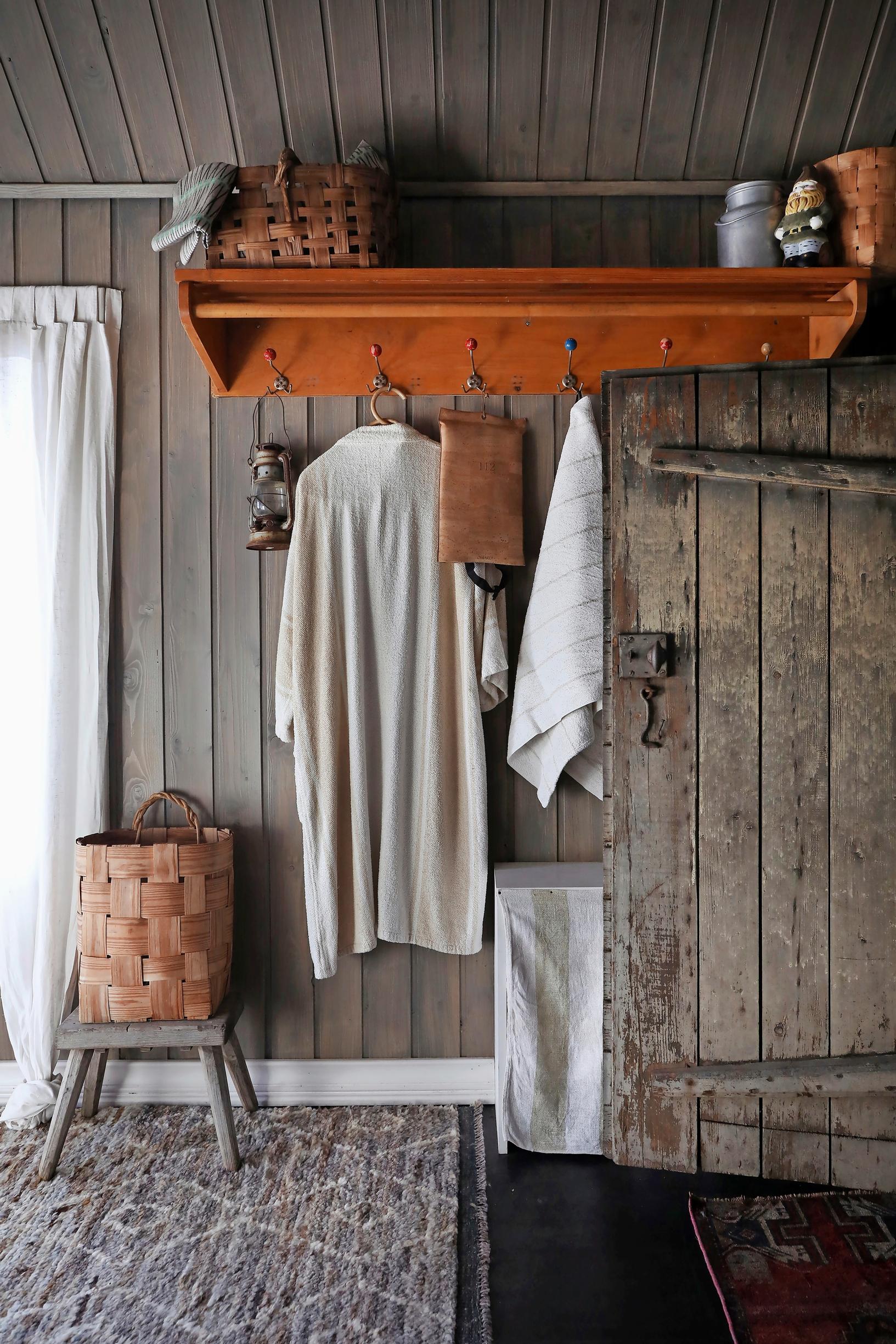 A towel and clothes on the coat rack by the sauna door, splint basket on the stool