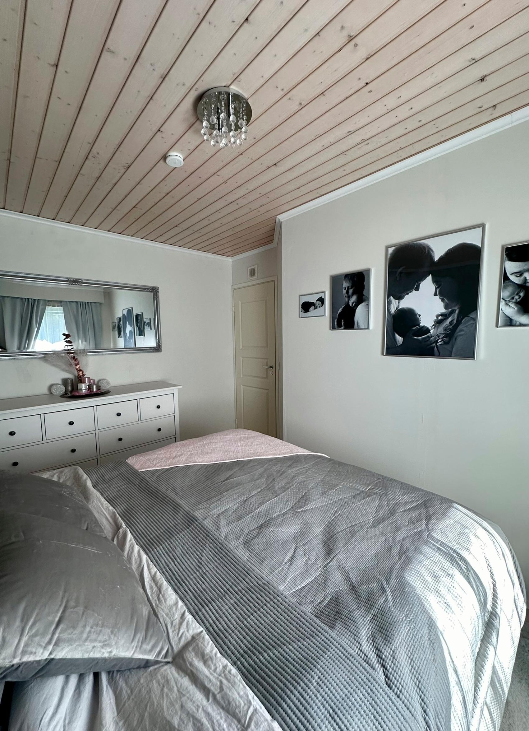 The double bed is shown from head to foot, with a white chest of drawers along the side wall.