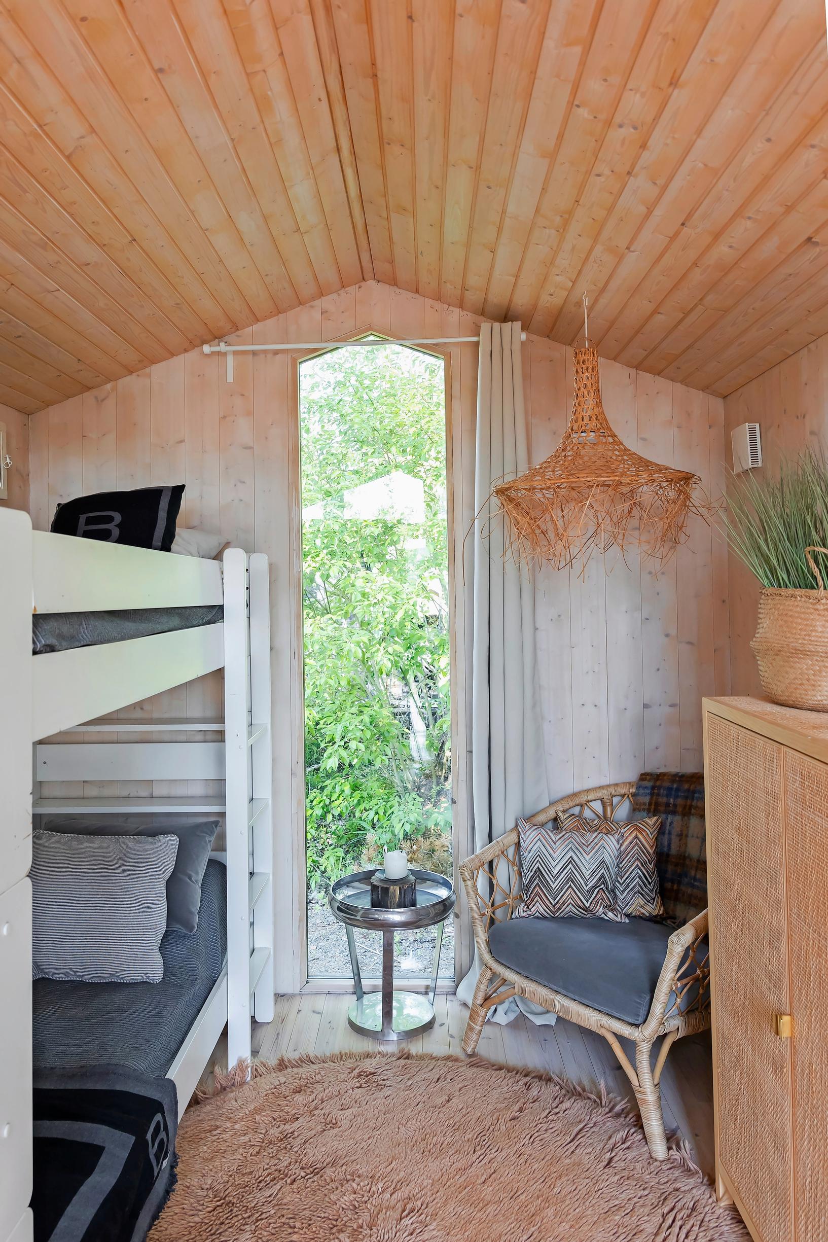 a bunk bed, a rattan chair and cabinet, a tall narrow window