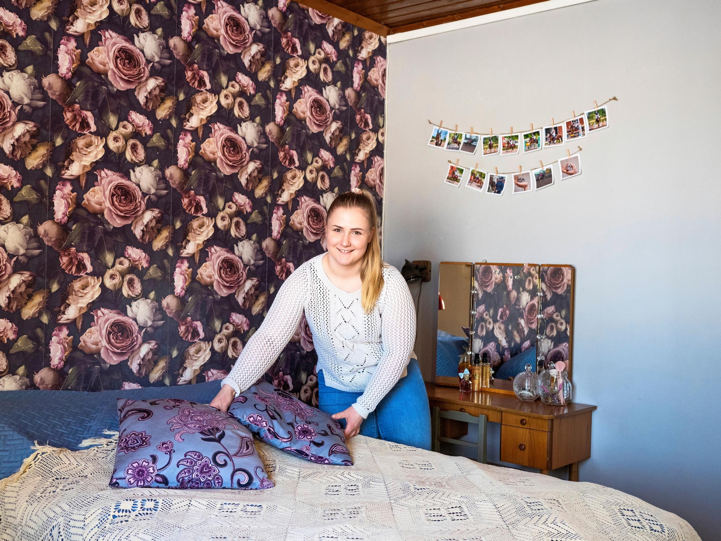 A woman arranging decorative pillows on a bed