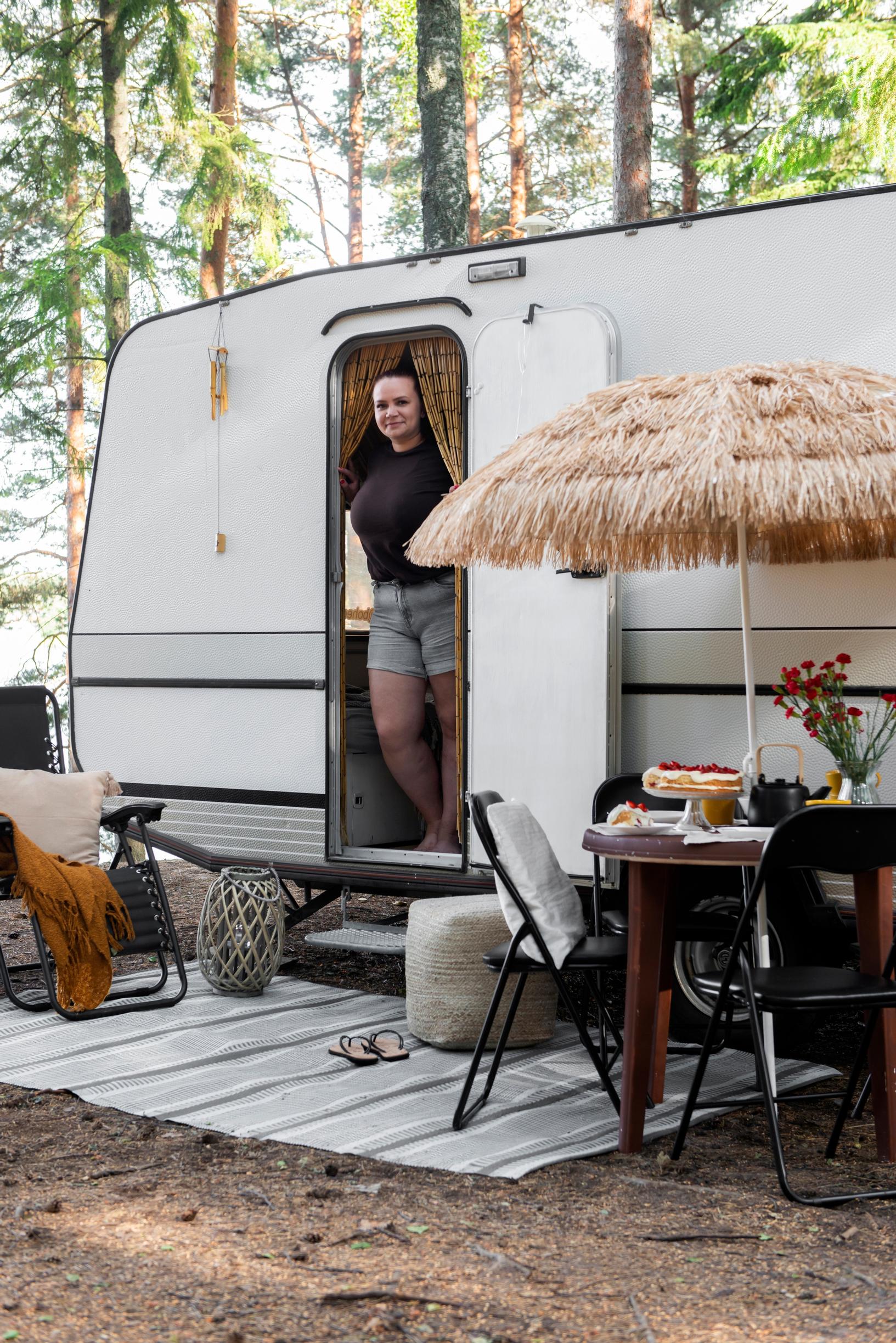 woman standing at the trailer doorway with a patio set in front