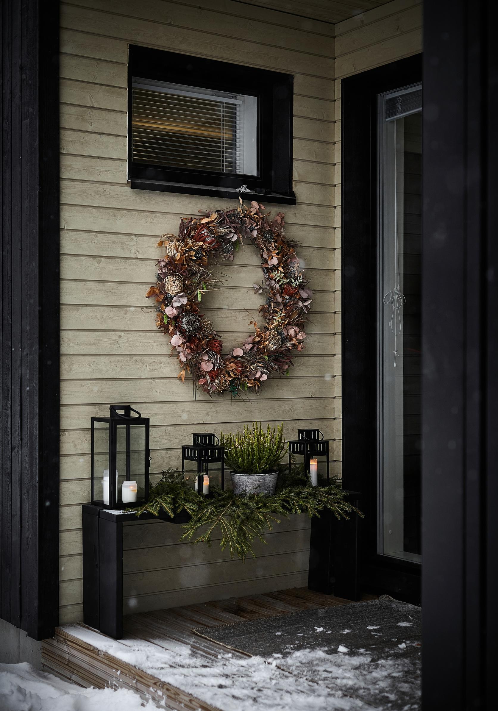 lanterns and a wreath on the terrace in front of the house’s entrance in winter