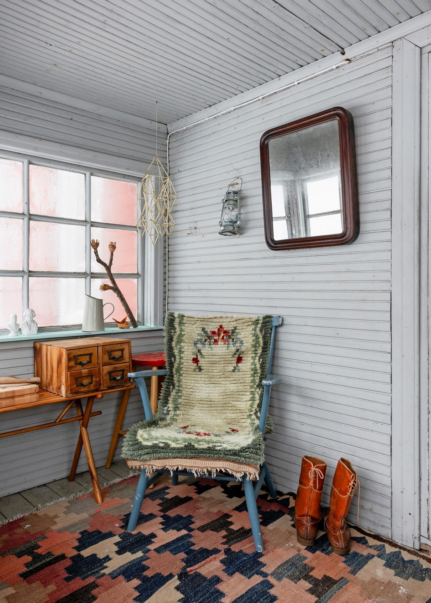 On the porch: a large rug, old blue chair, wooden cubby, and shoes