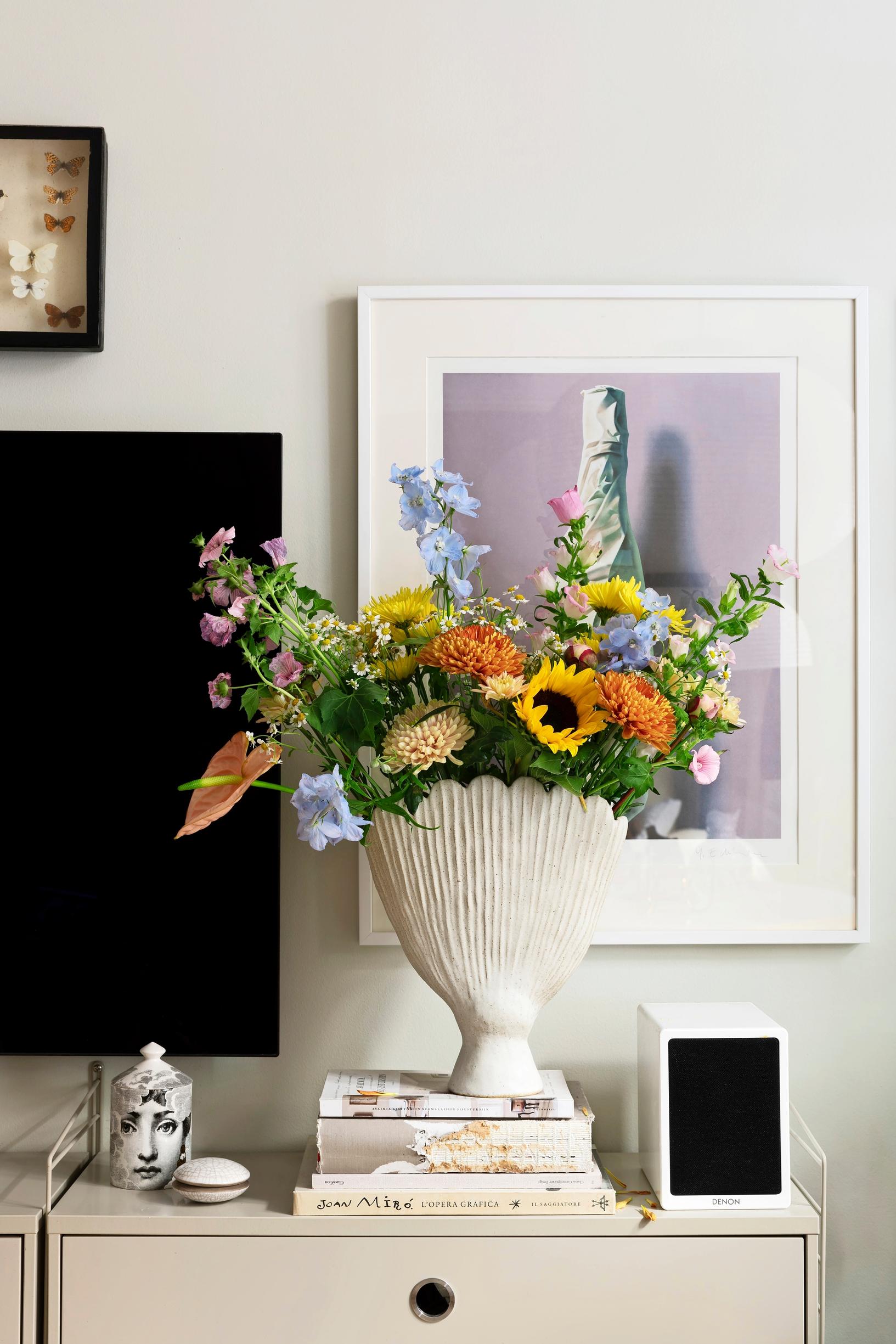 A vase made by ceramic artist Riikka Piippo with flowers atop a chest of drawers