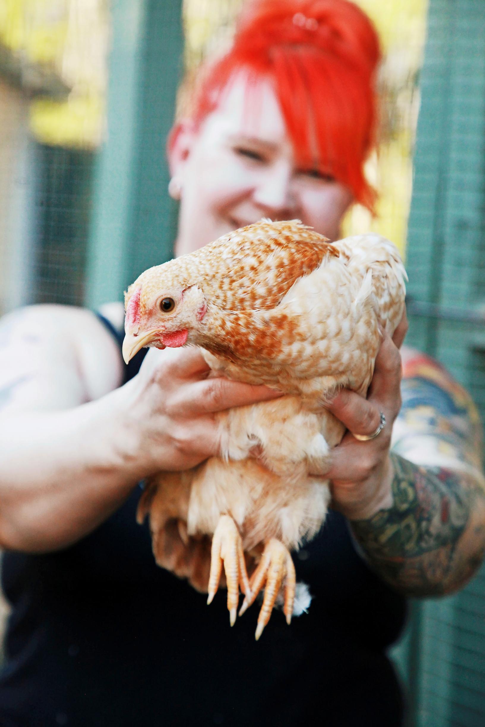 Anna-Kaisa holds a hen in her hands.