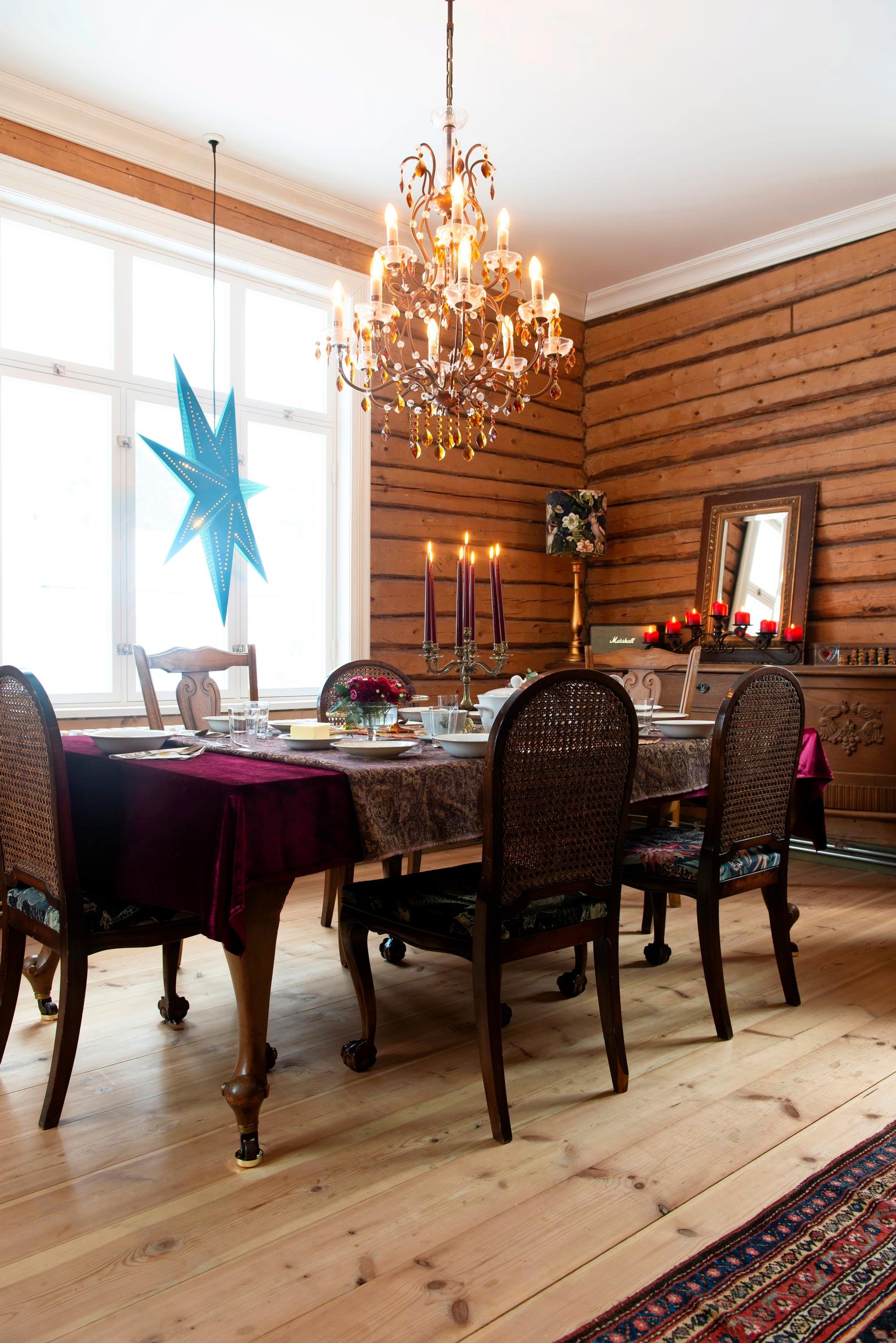 A large candle chandelier hangs above the dining table.