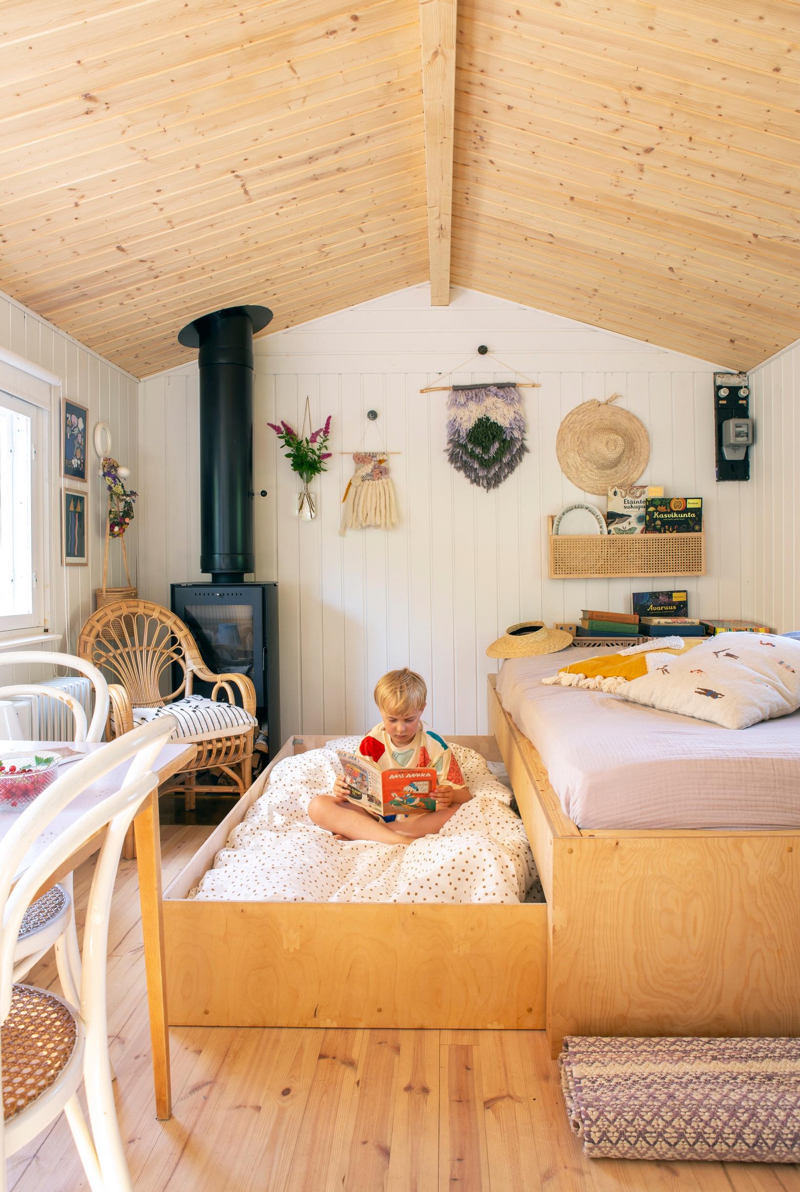 A boy reading in a pull-out wooden bed