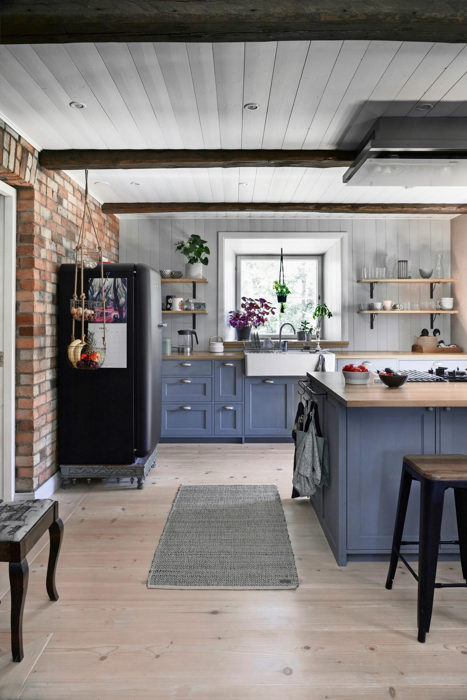 A blue kitchen and dark ceiling beams