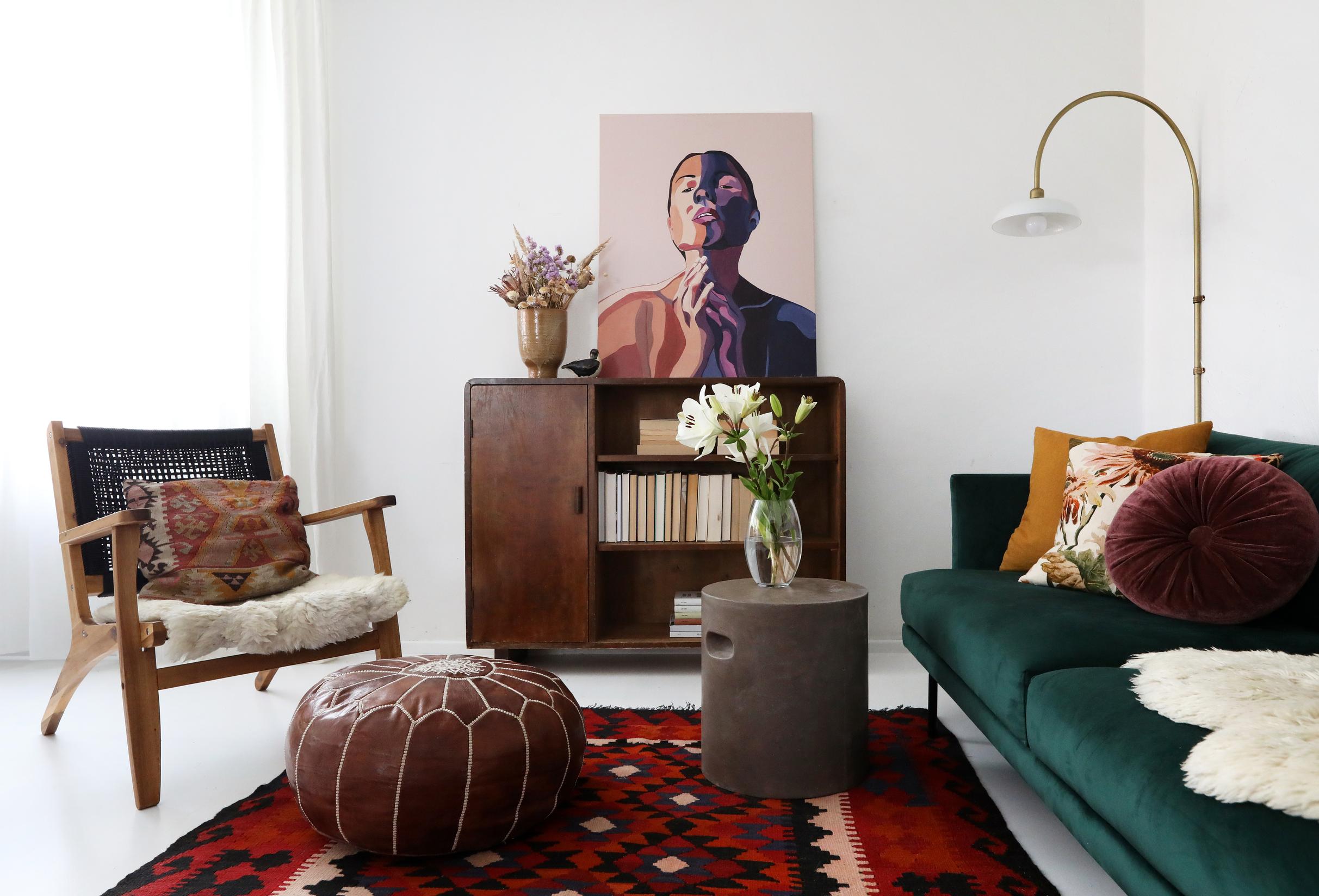 A leather pouf and an old sideboard accompany the modern sofa and small table.