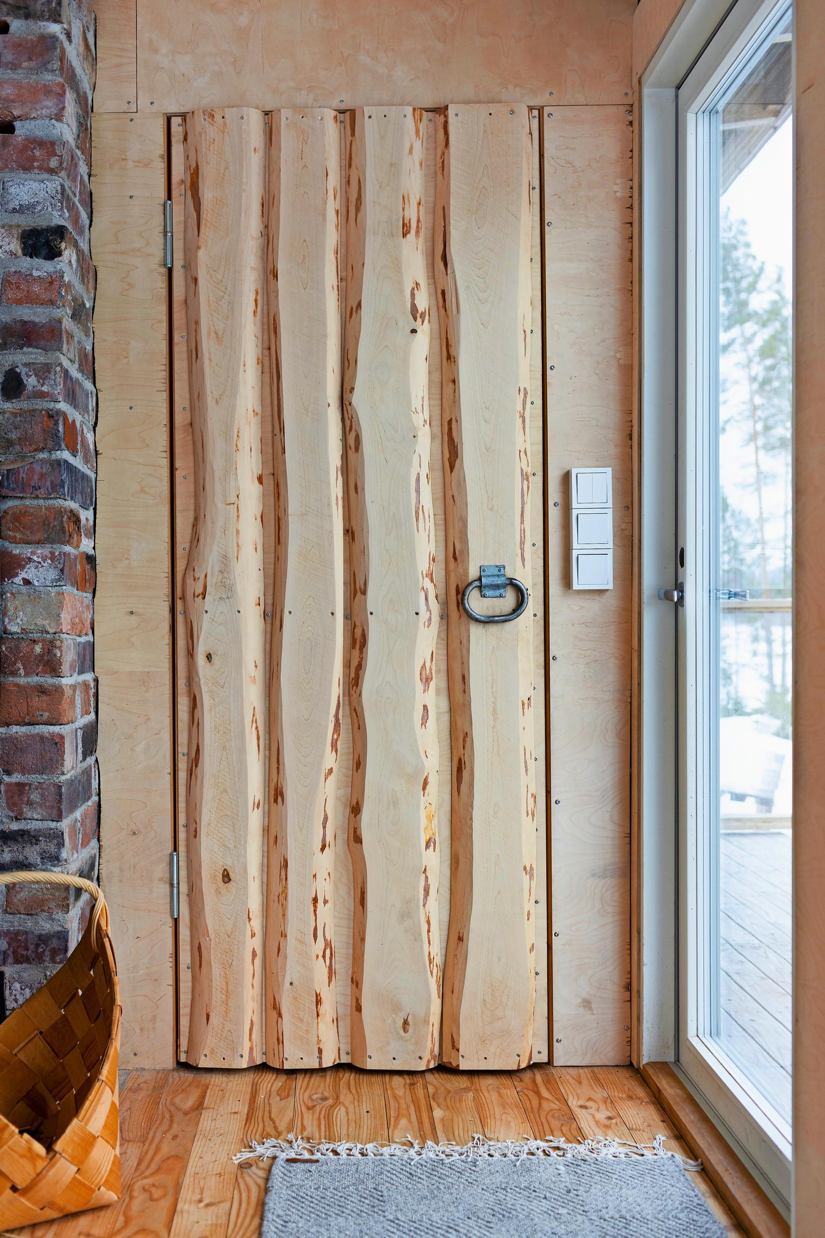 A plank door with a metal handle and a woven wooden basket.