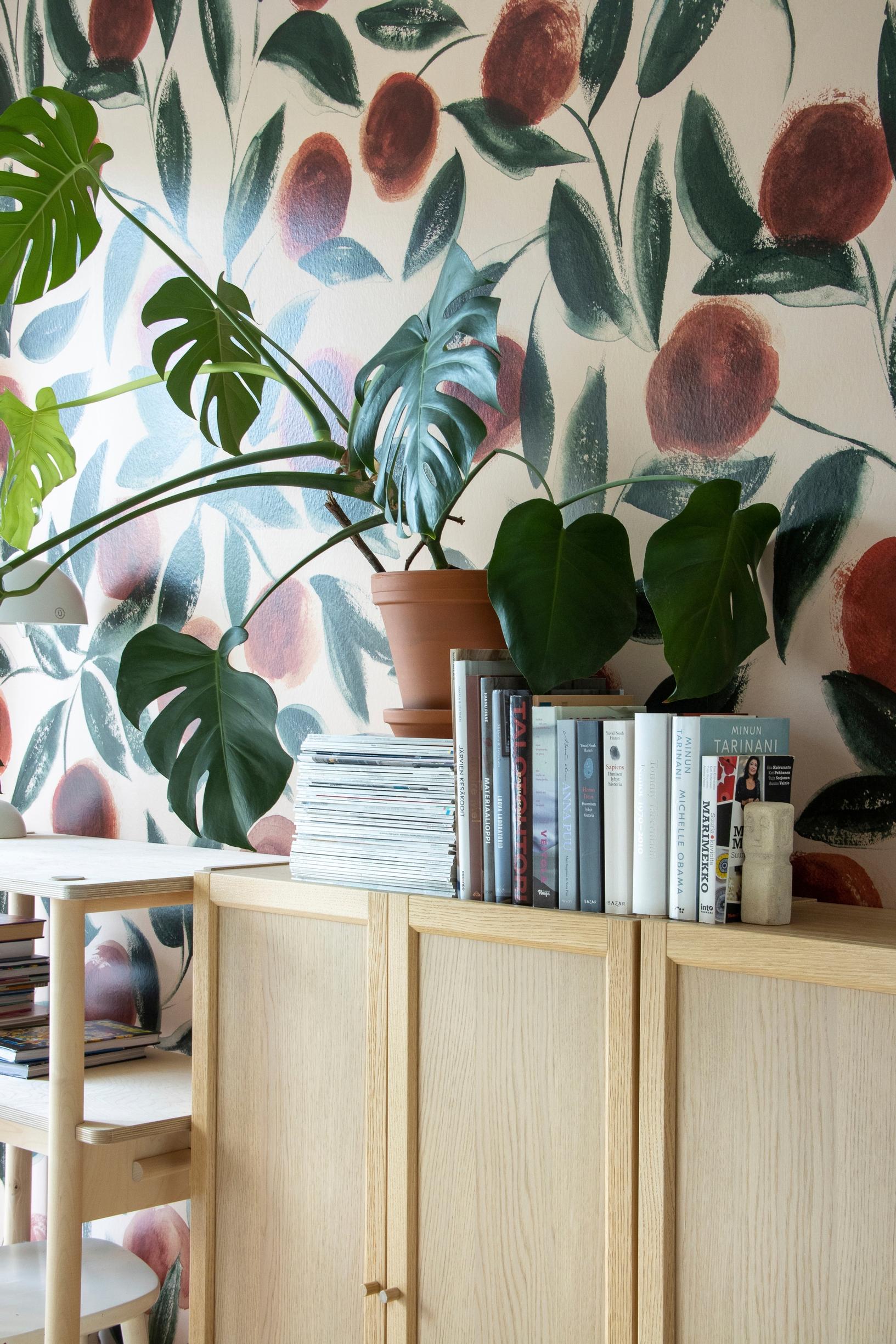 Arranging plants indoors: monstera in front of floral wallpaper