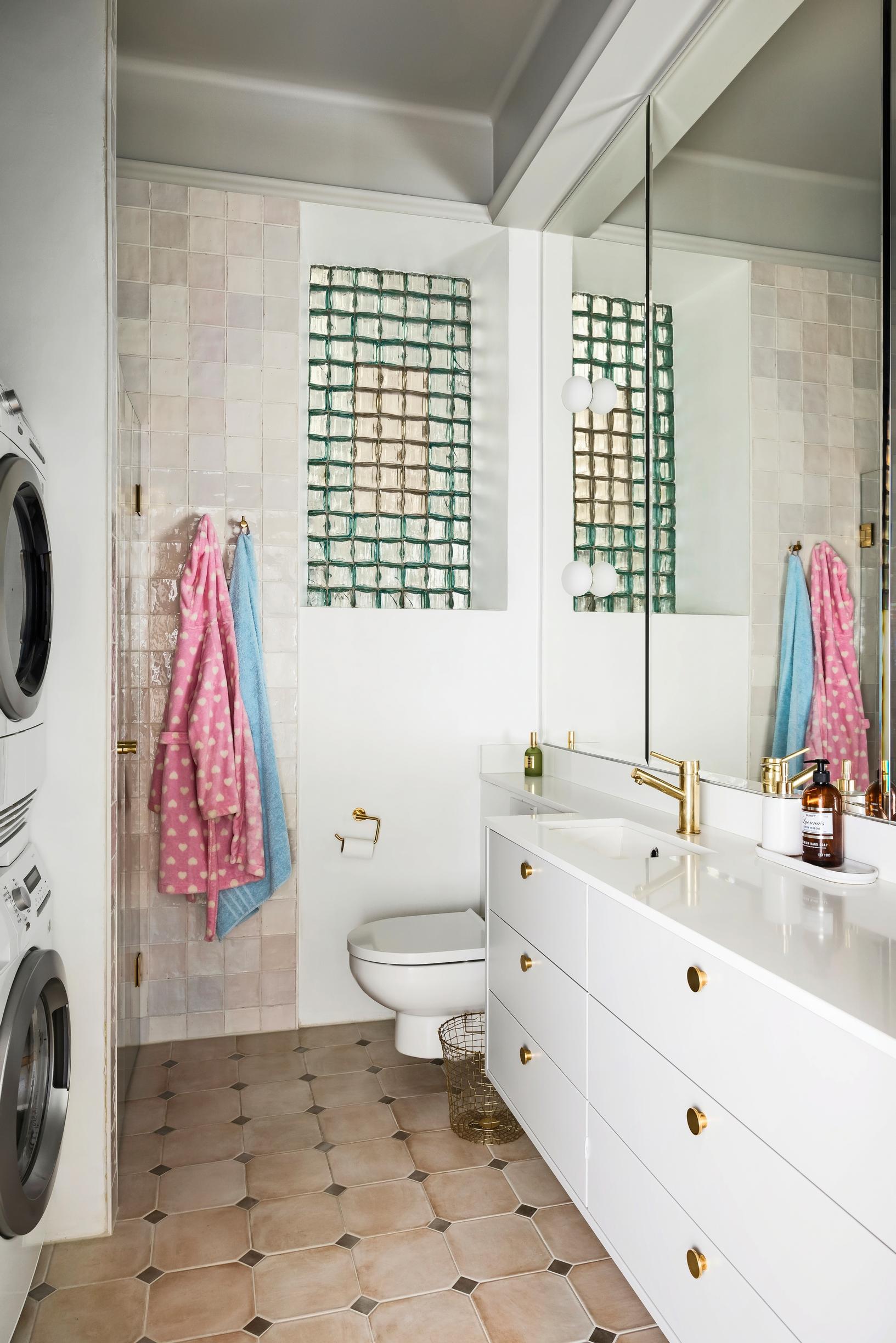 A stacked washer-dryer and a shower corner in a long, narrow bathroom