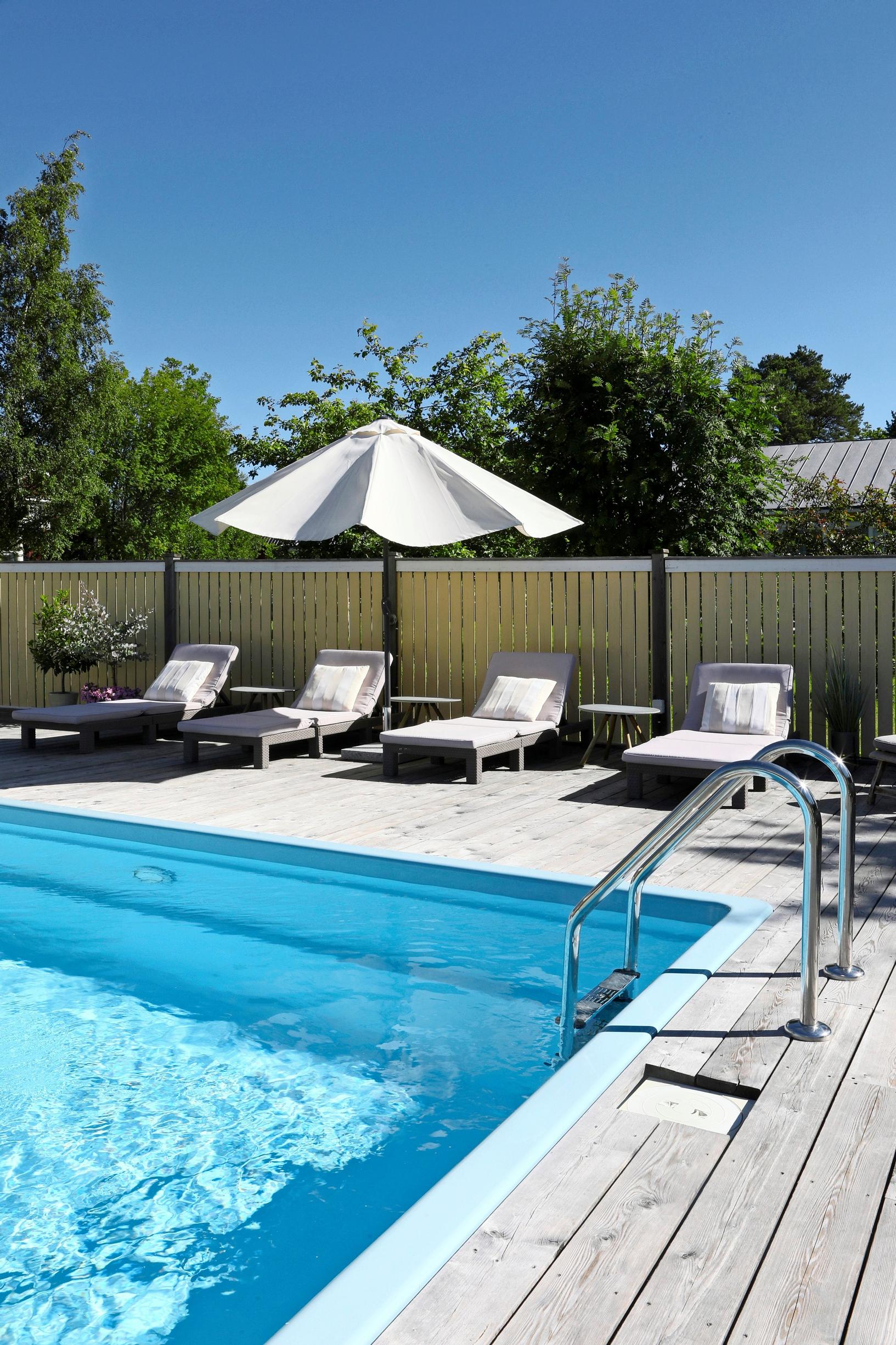 White sun loungers and a sun umbrella by the edge of the swimming pool