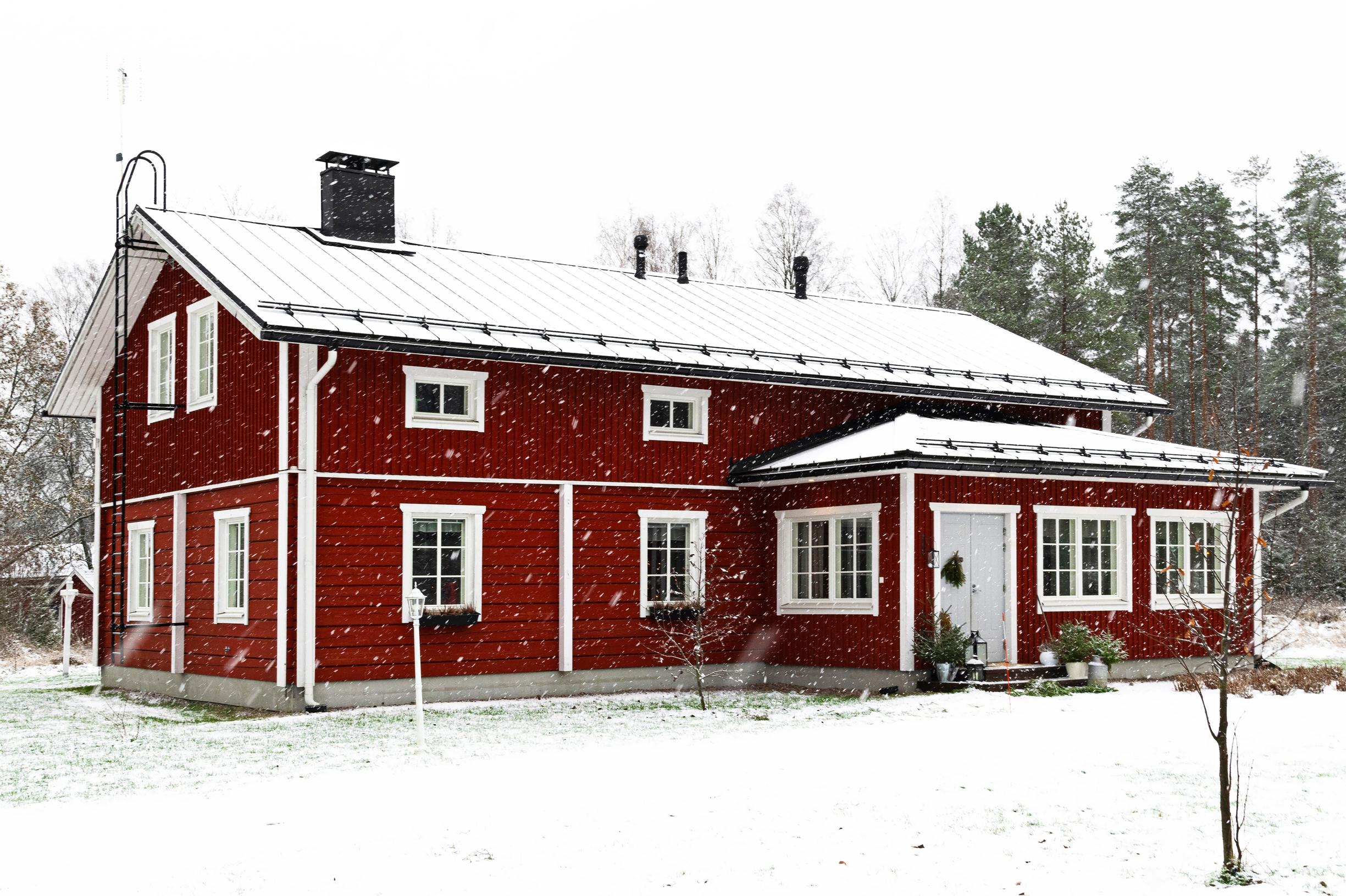 Red log house during snowfall