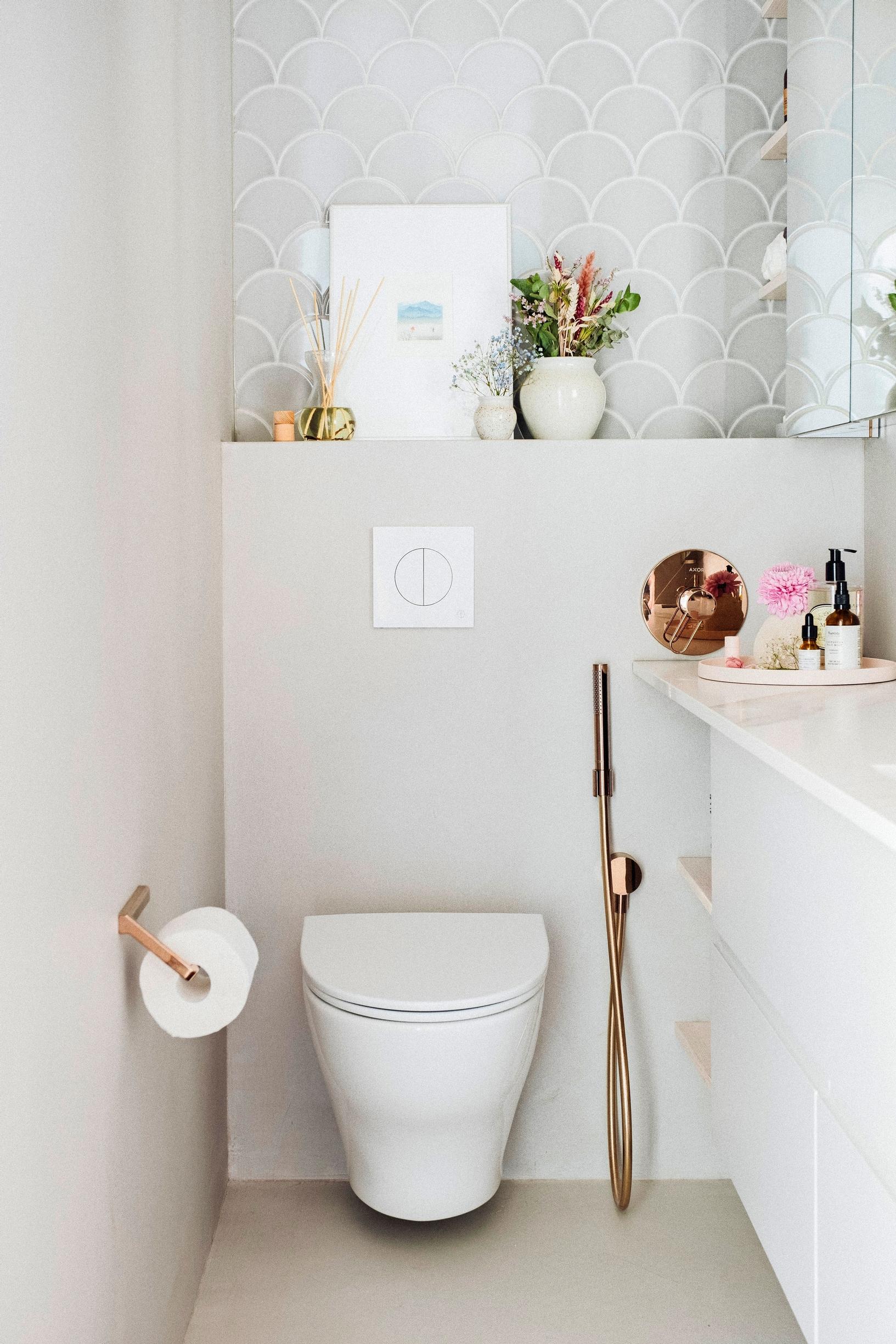 Small white WC with microcement walls and rose gold fixtures