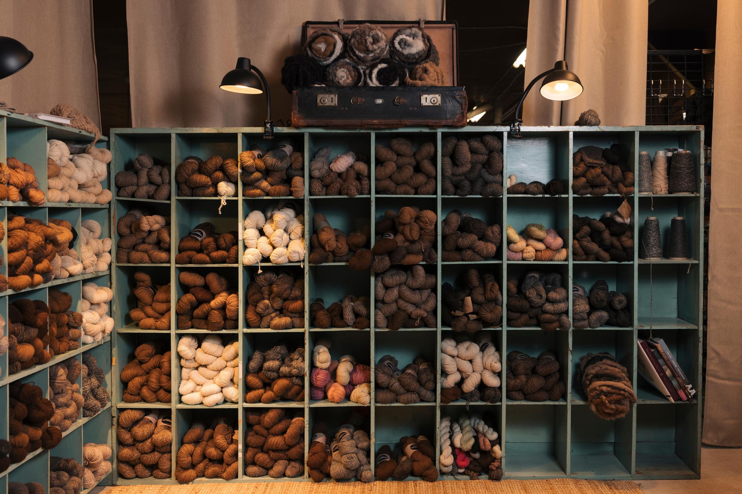 Skeins of differently colored wool yarn in a wall cubby