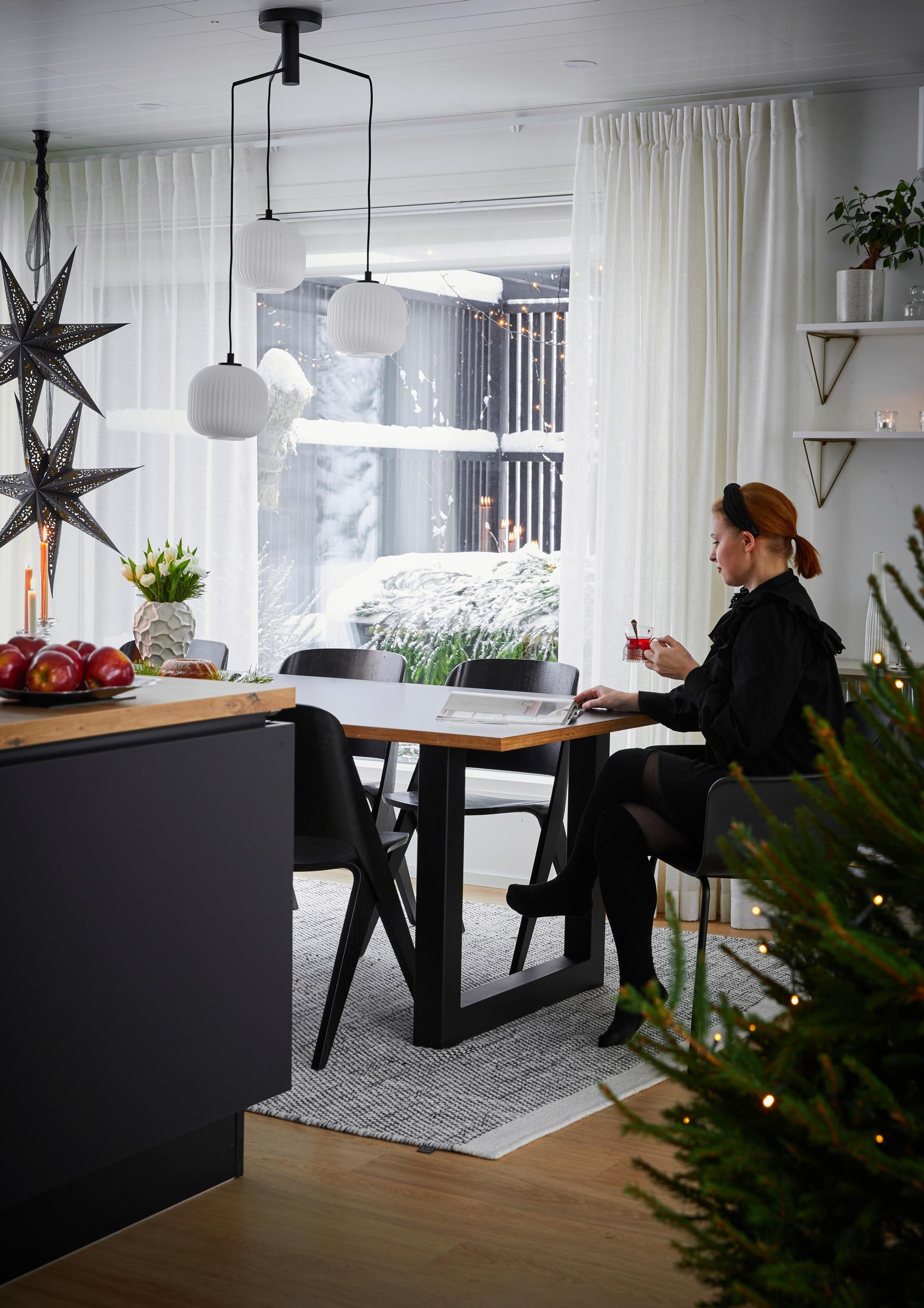 Julia sits at the table, with a Christmas tree and paper stars