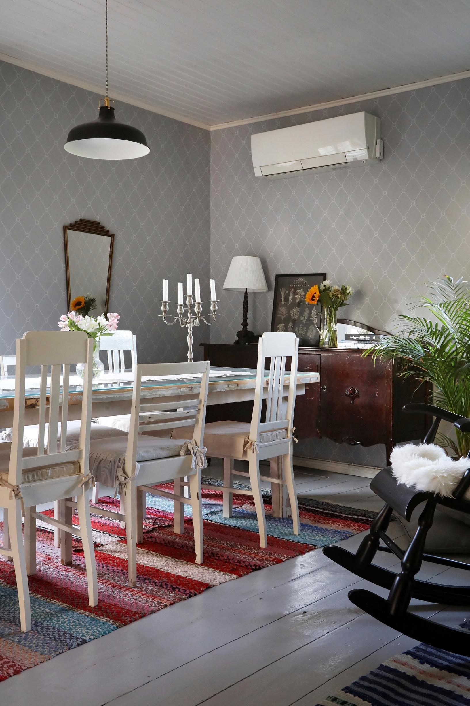 Old wooden chairs around the table, rag rug, and plank floor