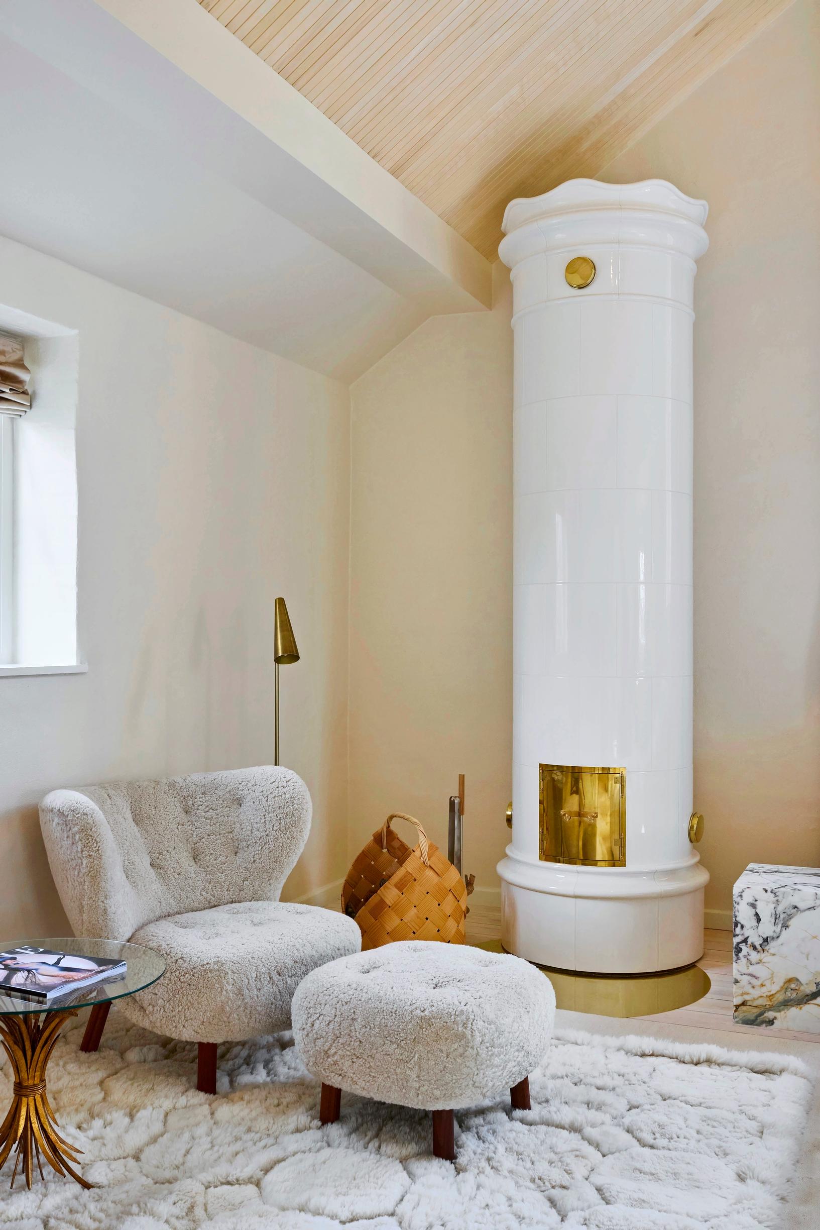 A tiled stove and a plush armchair in the large upstairs bedroom