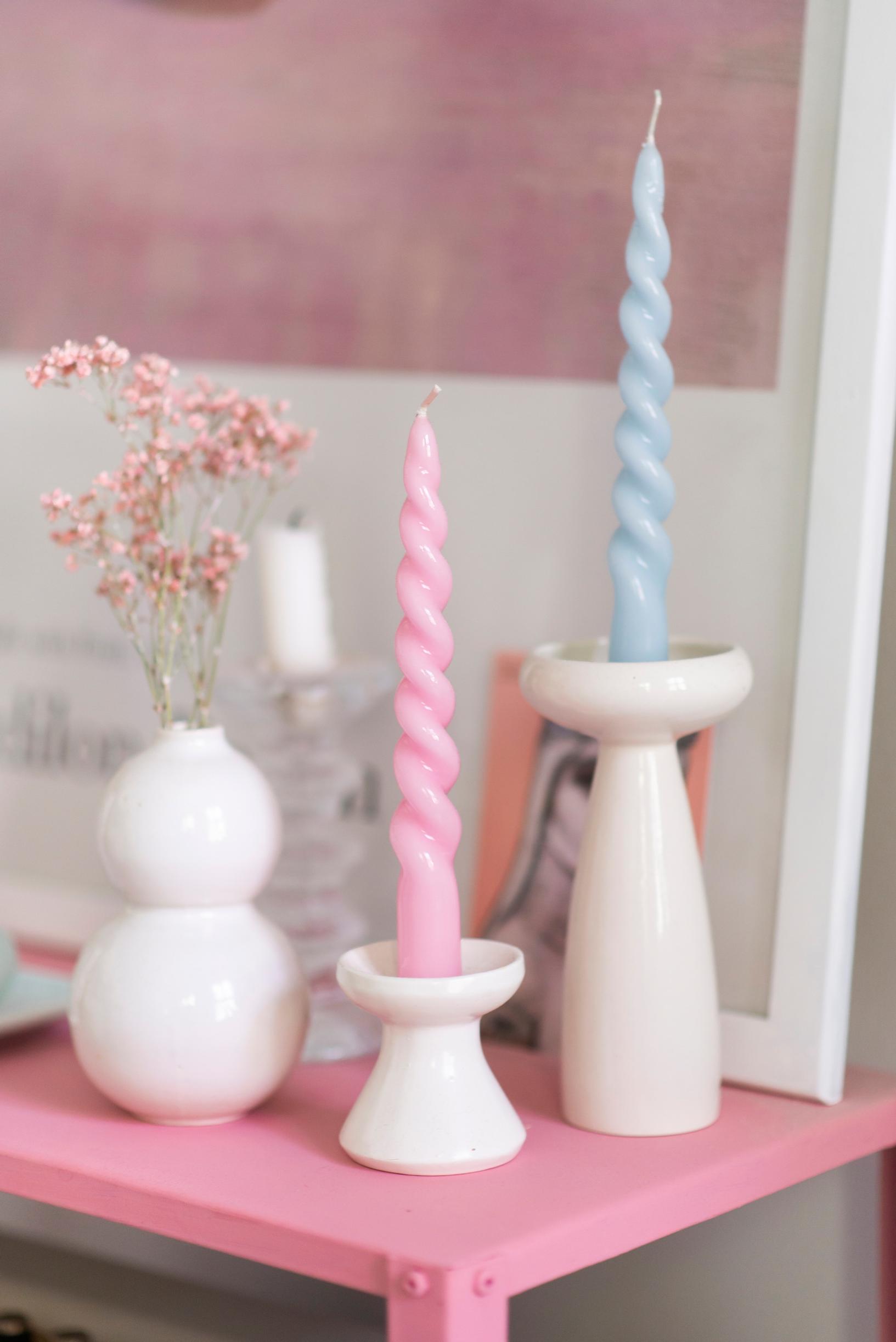 White candlesticks and twisted candles on a pink surface