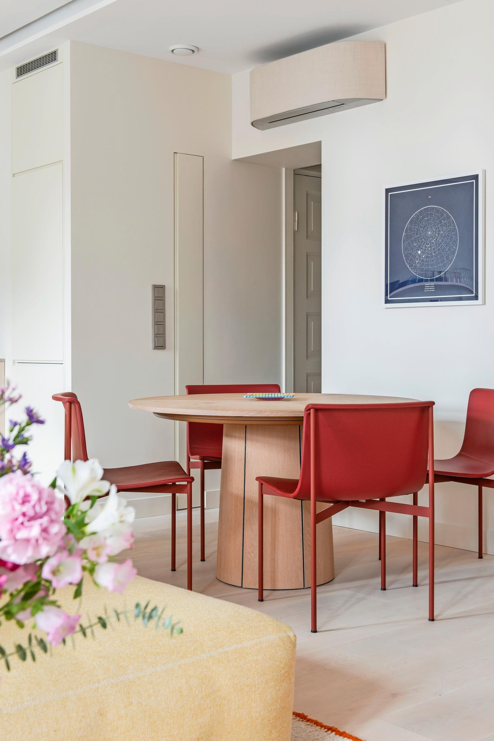 An extendable oak-veneered dining table and brick-red chairs in the dining area