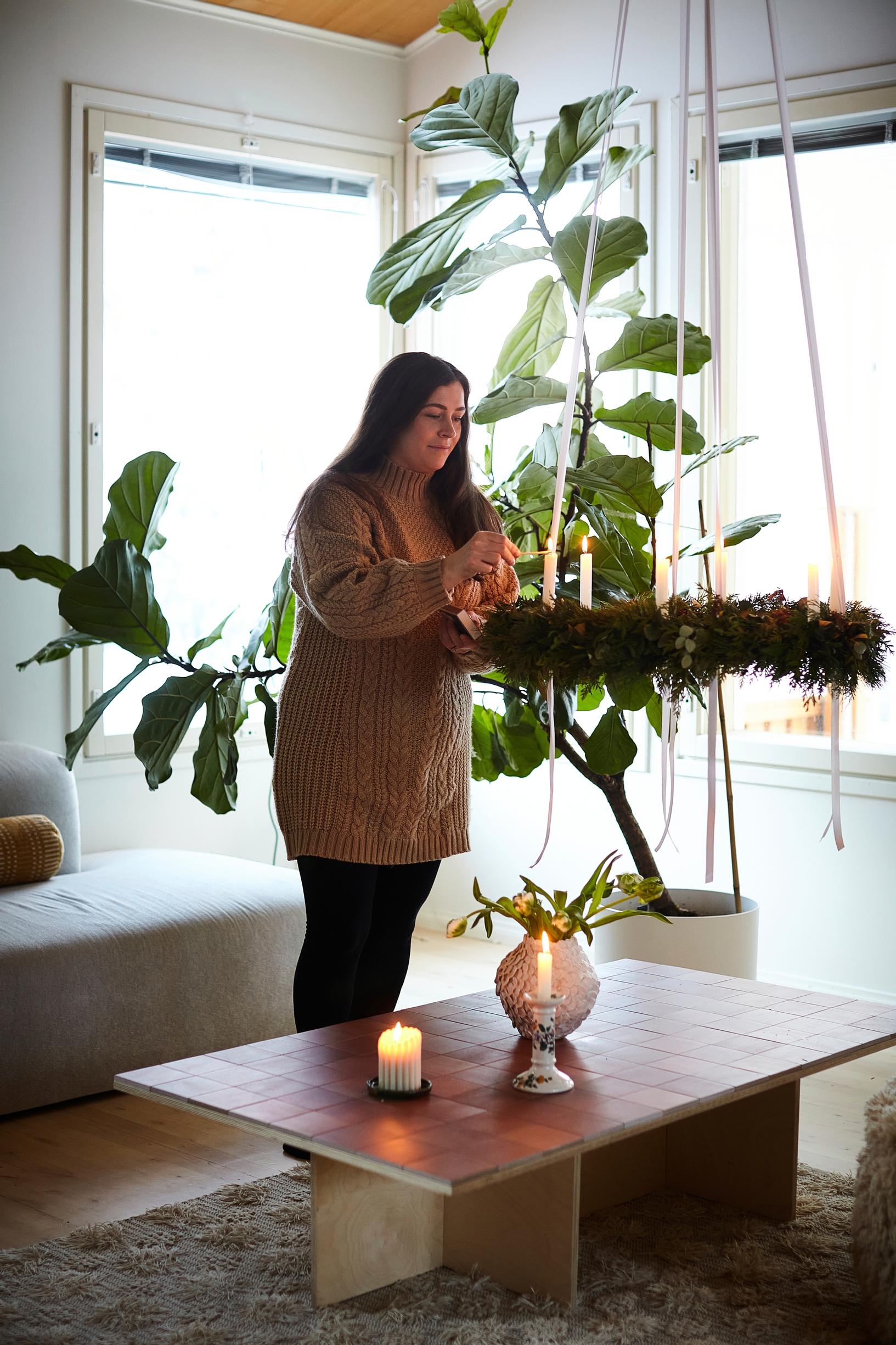 Jade Anetjärvi places candles in a wreath of fir branches in the living room