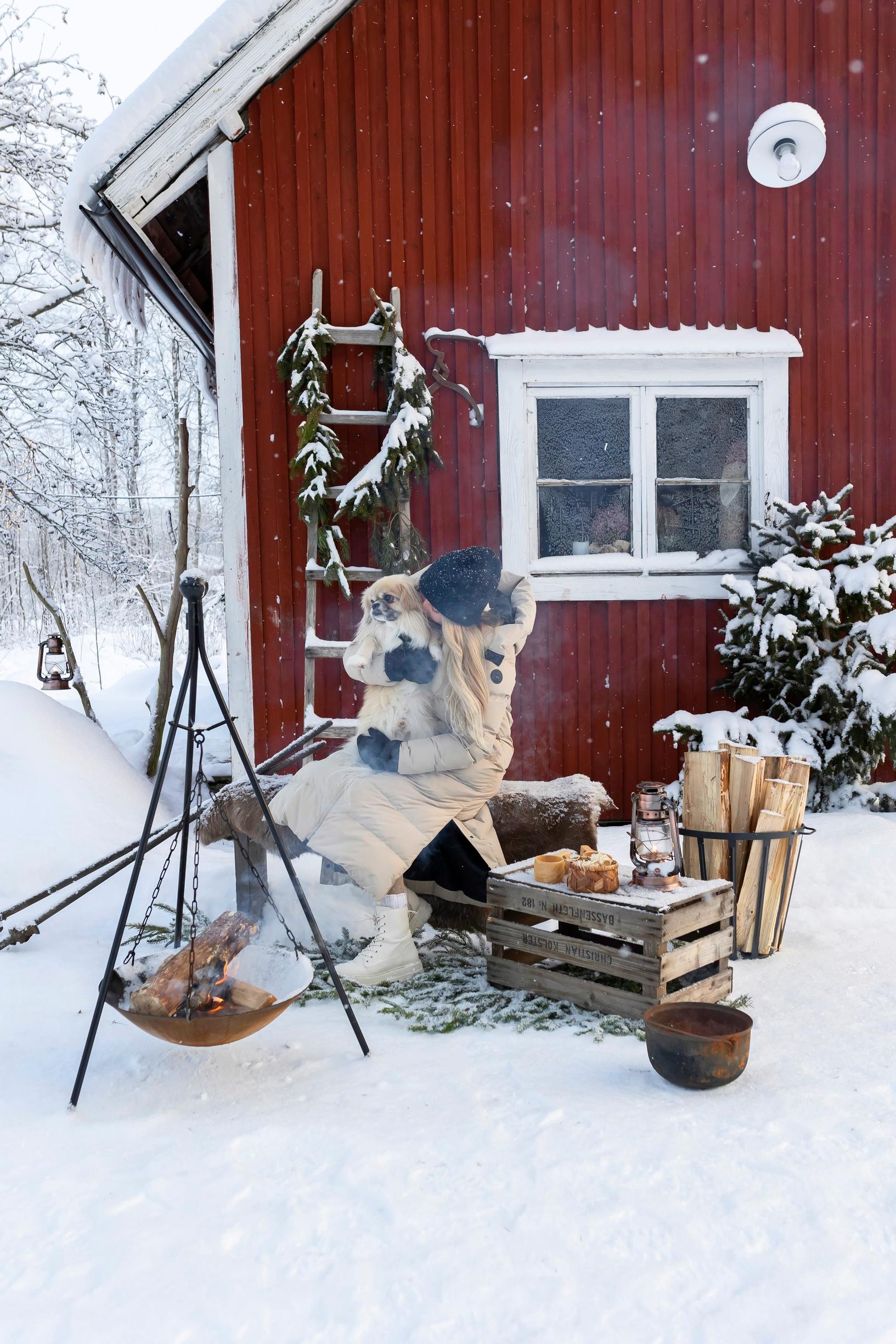 Meeri sits by the campfire with the dog