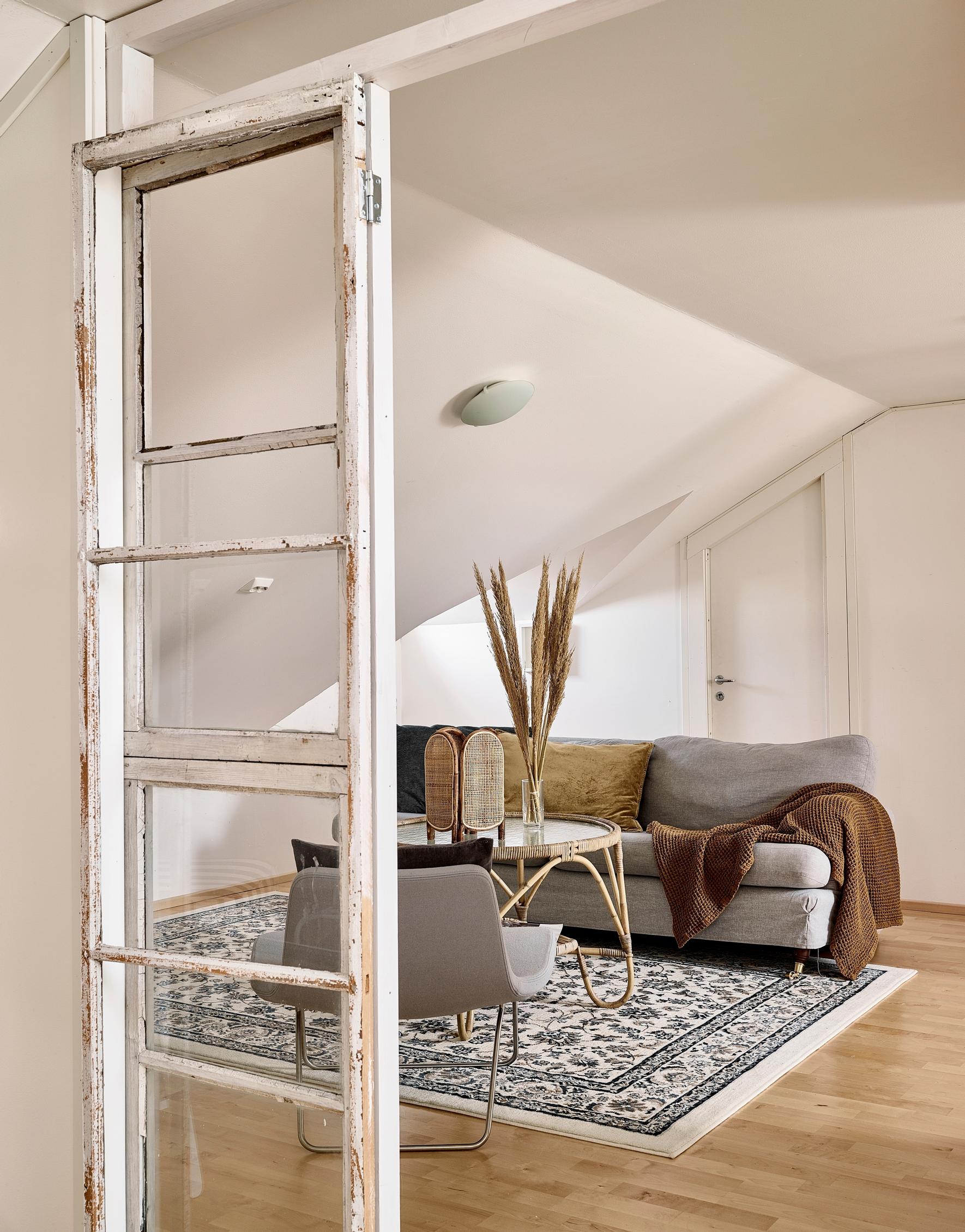 A pair of glass doors repurposed from old windows encloses the living area of a wooden house.