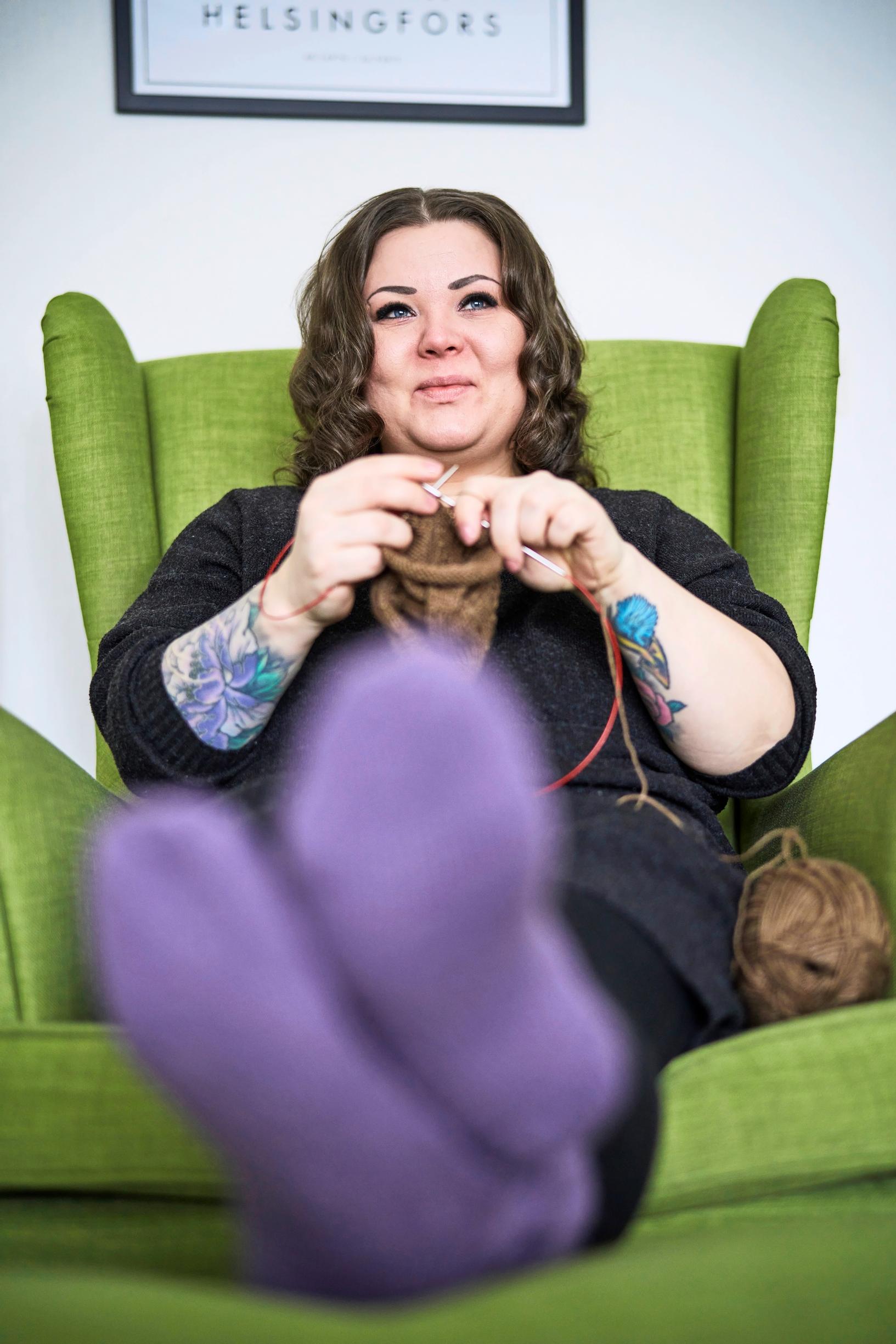 Niina Laitinen knitting in an armchair