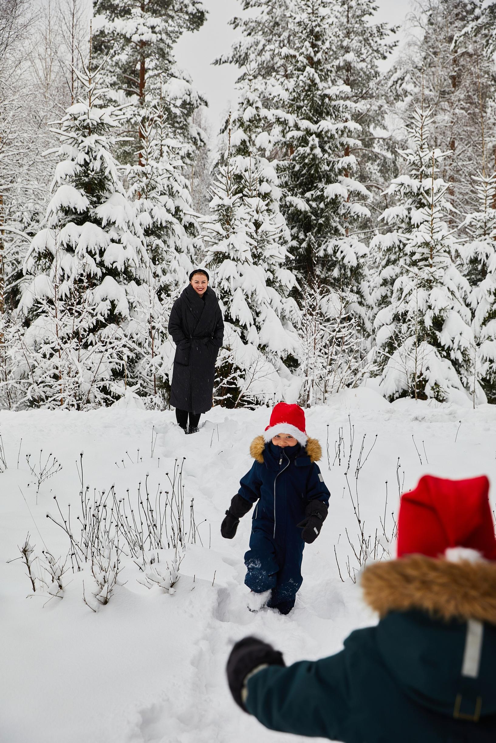 a mother and little boys wearing elf hats in a snowy forest