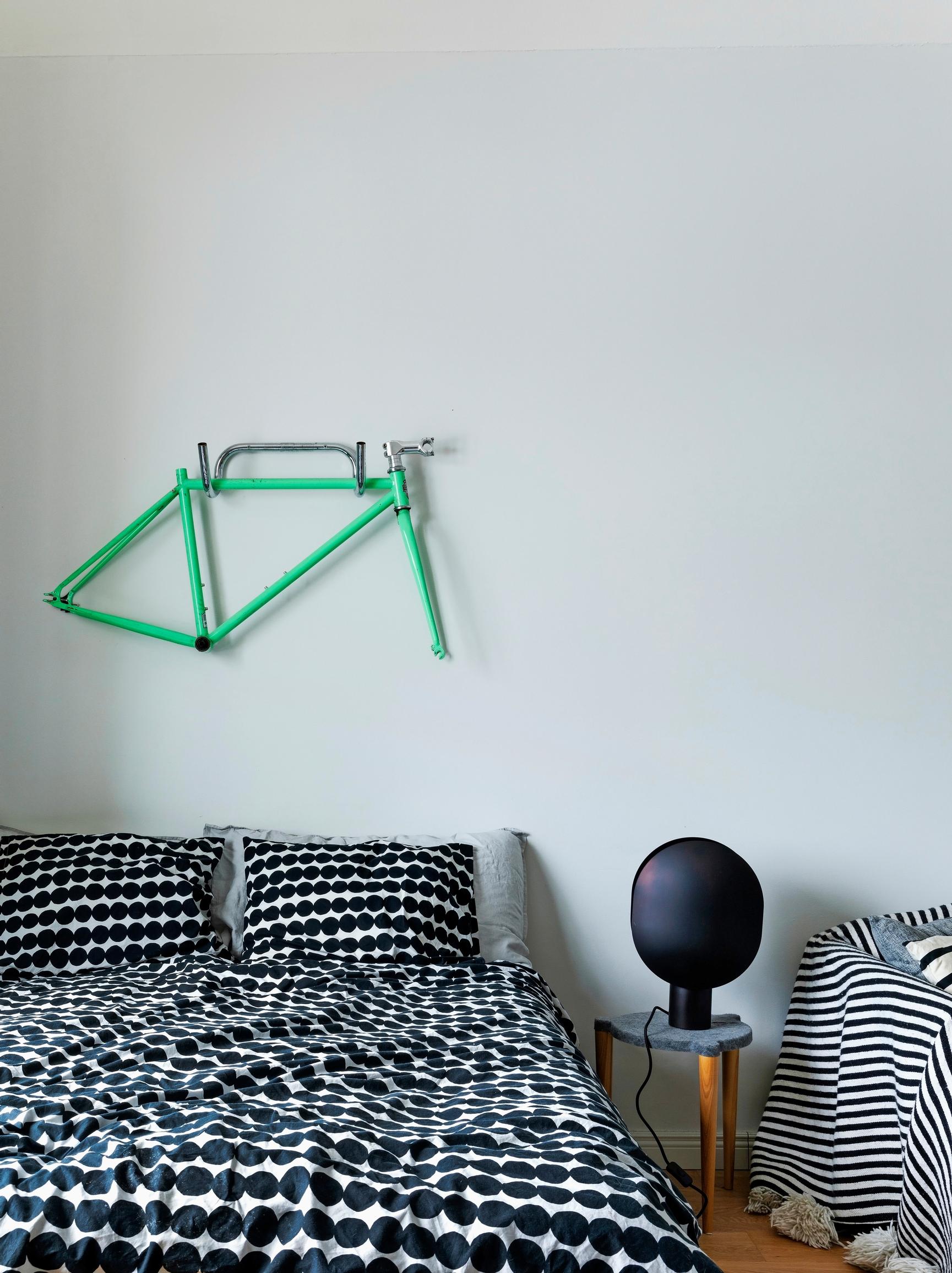 Bedroom with a made bed and a bike frame on the wall.
