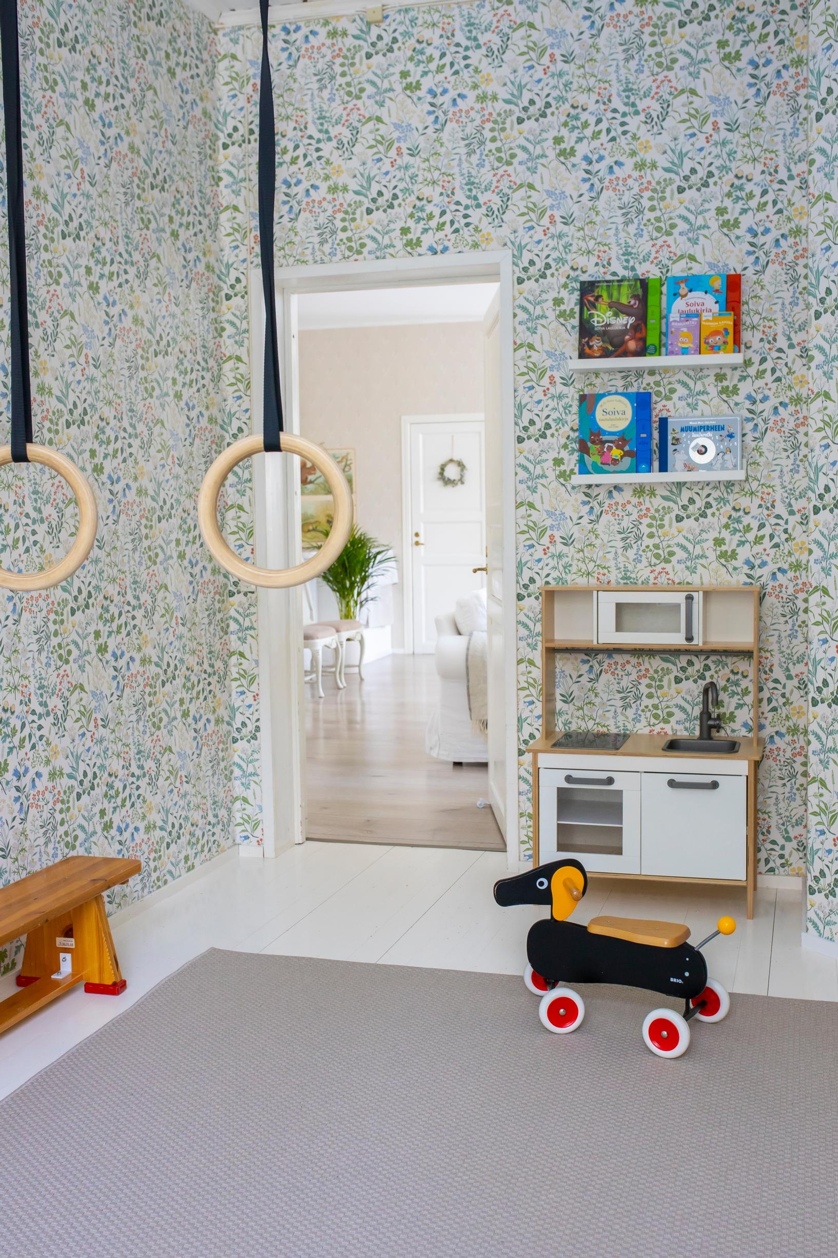 The play kitchen and bookshelves in the children’s room. Gymnastic rings hang in the foreground.