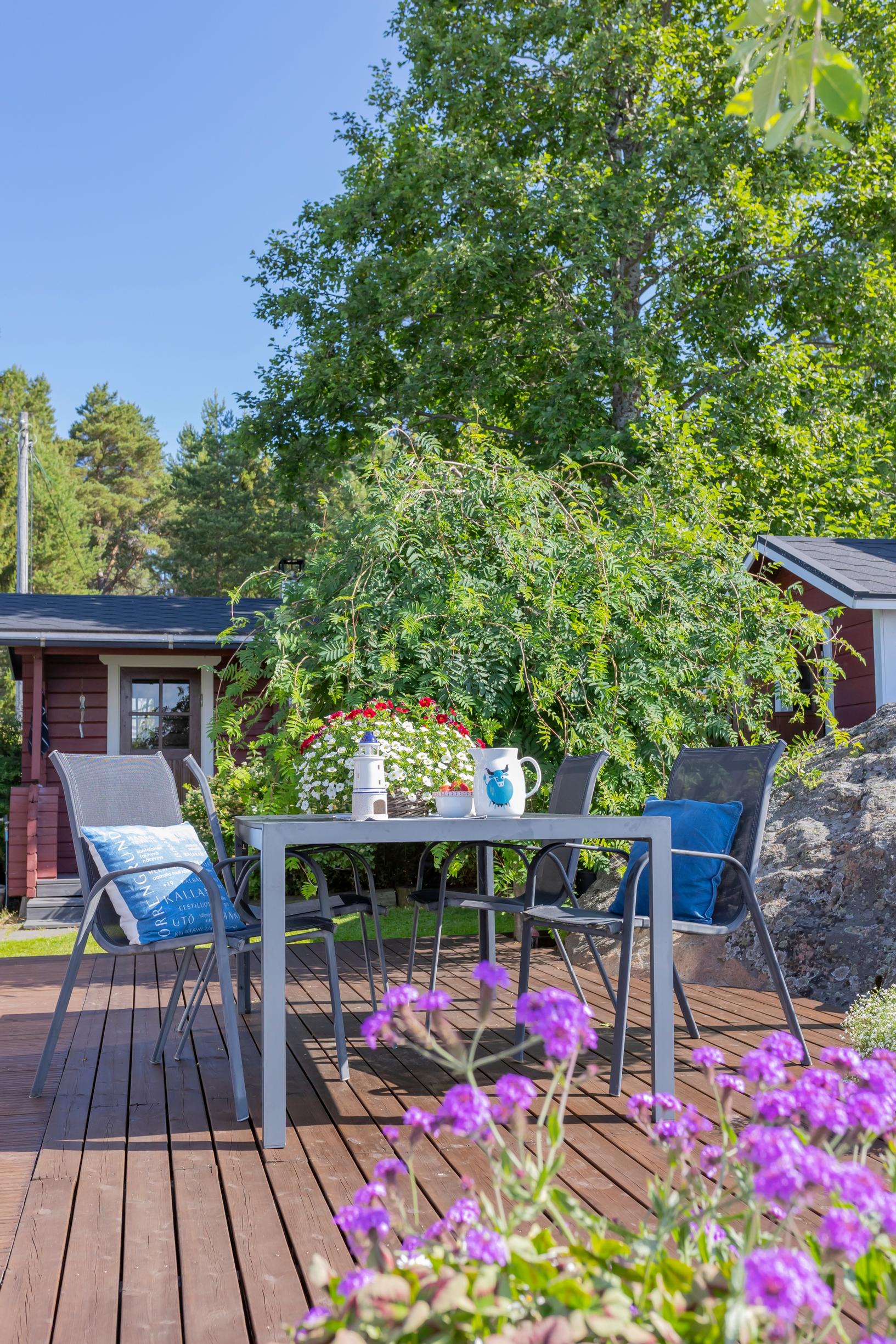 a patio set on the terrace, a building, and summer flowers