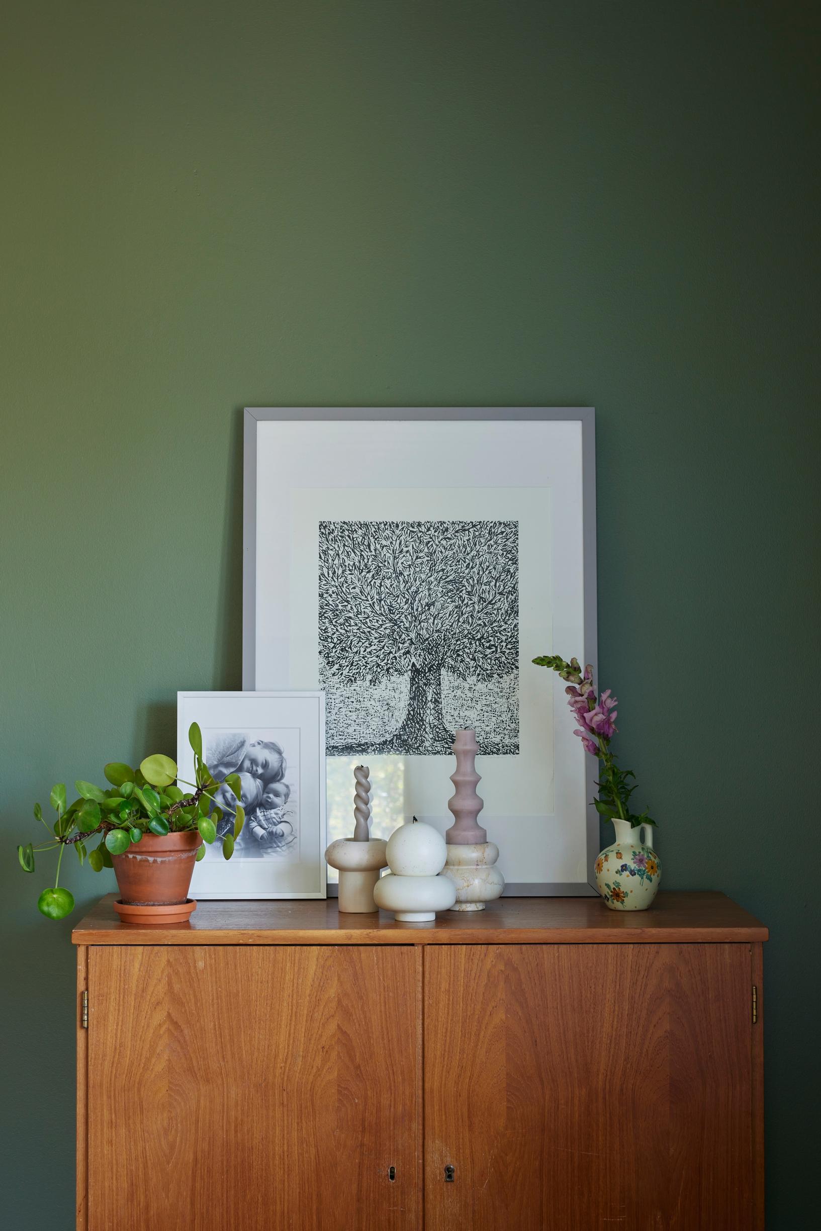 Artwork and candleholders on top of a cupboard