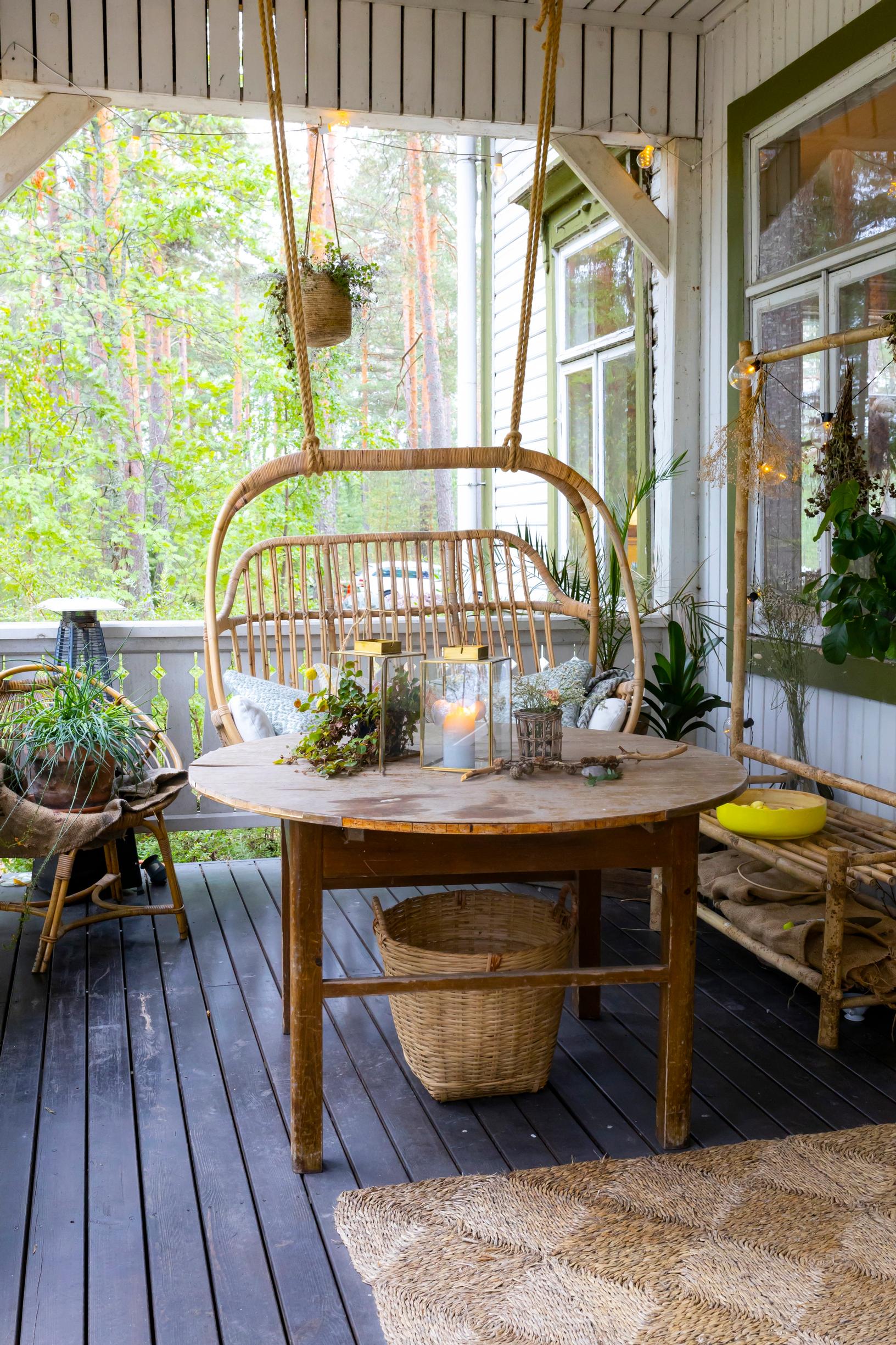 Hanging rattan chair on the villa’s terrace, round table, and lanterns.