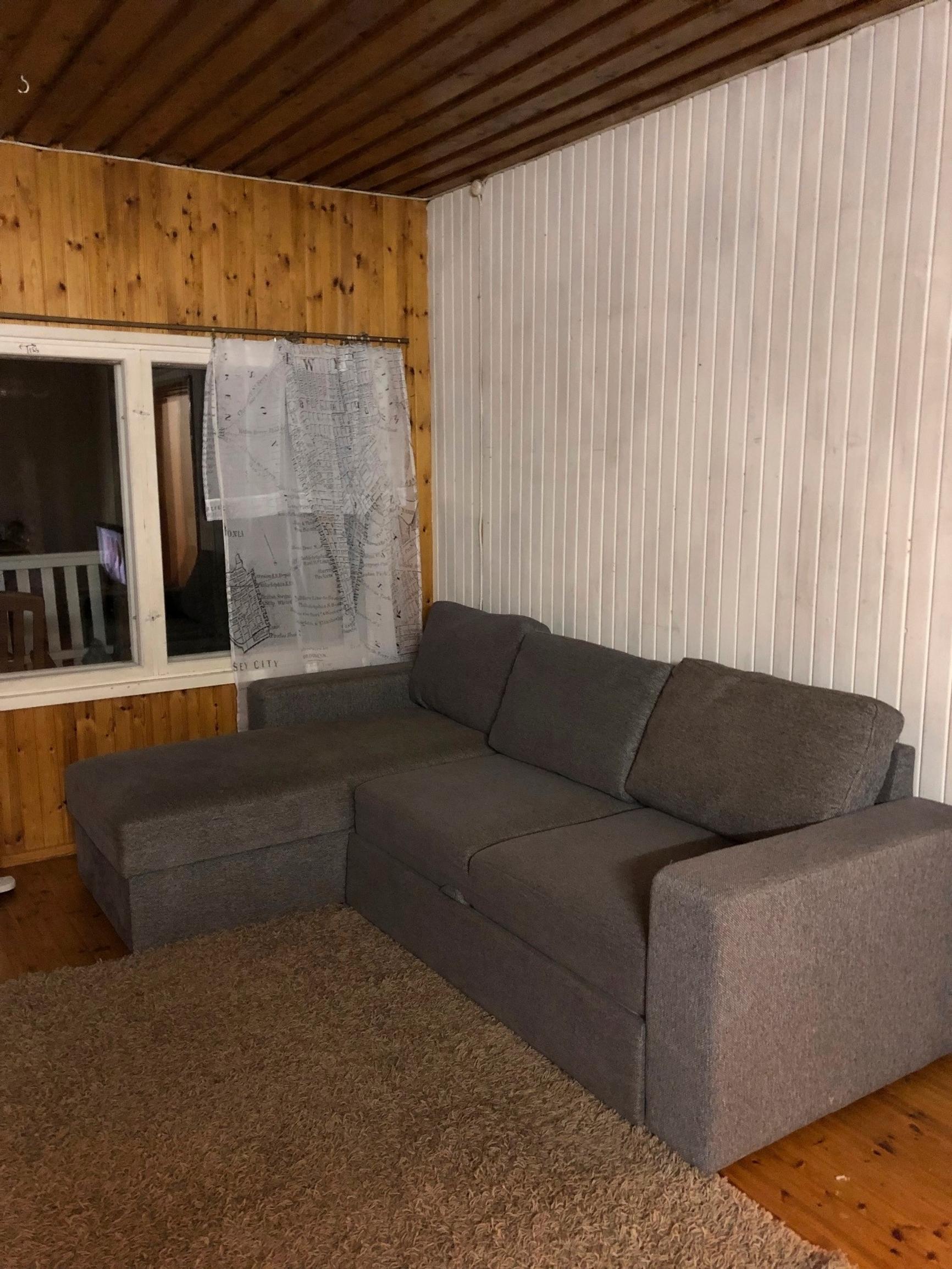 A dark corner sofa, a large rug, and walls of different colors
