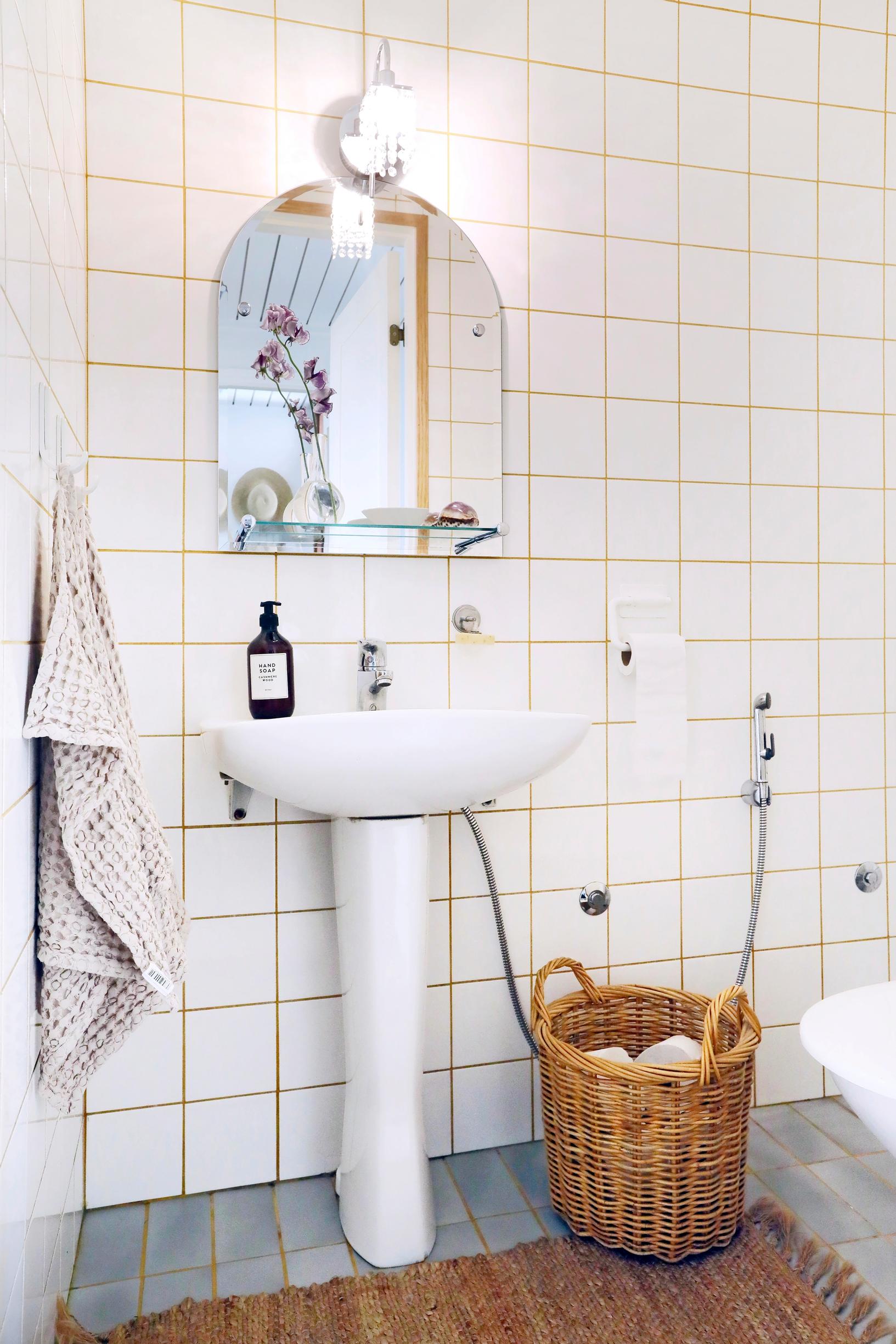 Photo of the toilet with white tiling and beige grout.